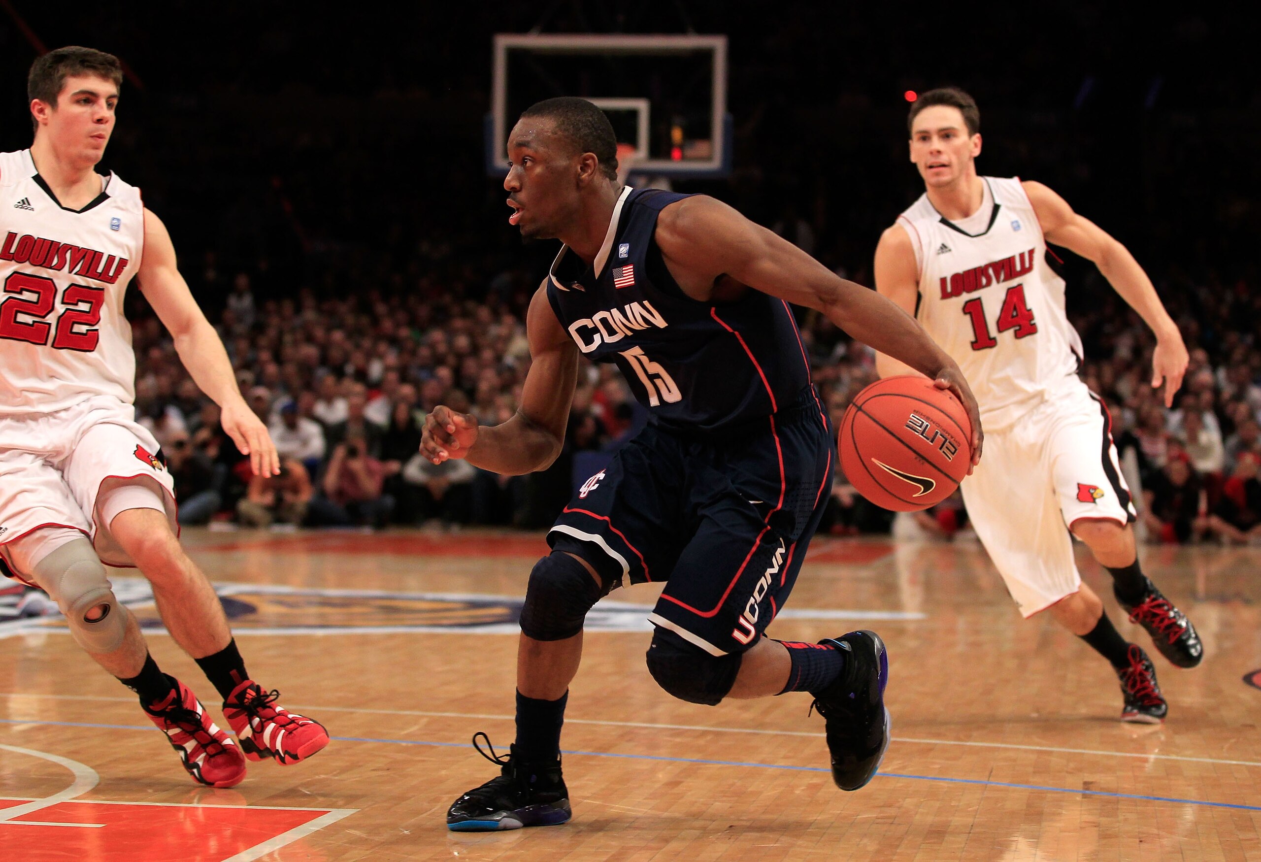 NEW YORK, NY - MARCH 12: Kemba Walker #15 of the Connecticut Huskies drives with the ball against Elisha Justice #22 and Kyle Kuric #14 of the Louisville Cardinals during the championship of the 2011 Big East Men's Basketball Tournament presented by Ameri