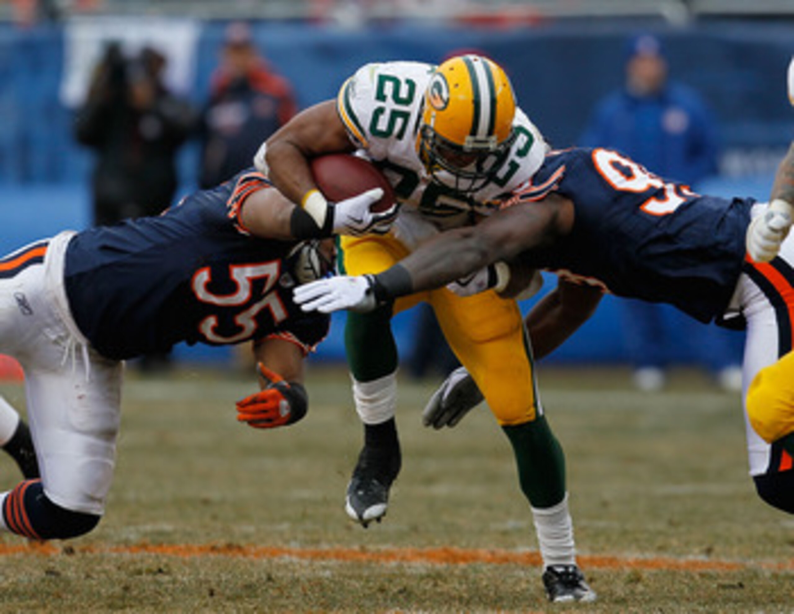 CHICAGO - DECEMBER 13: Ryan Grant #25 of the Green Bay Packers tries to break away from Lance Briggs #55 and Gaines Adams #99 of the Chicago Bears at Soldier Field on December 13, 2009 in Chicago, Illinois. The Packers defeated the Bears 21-14. (Photo by