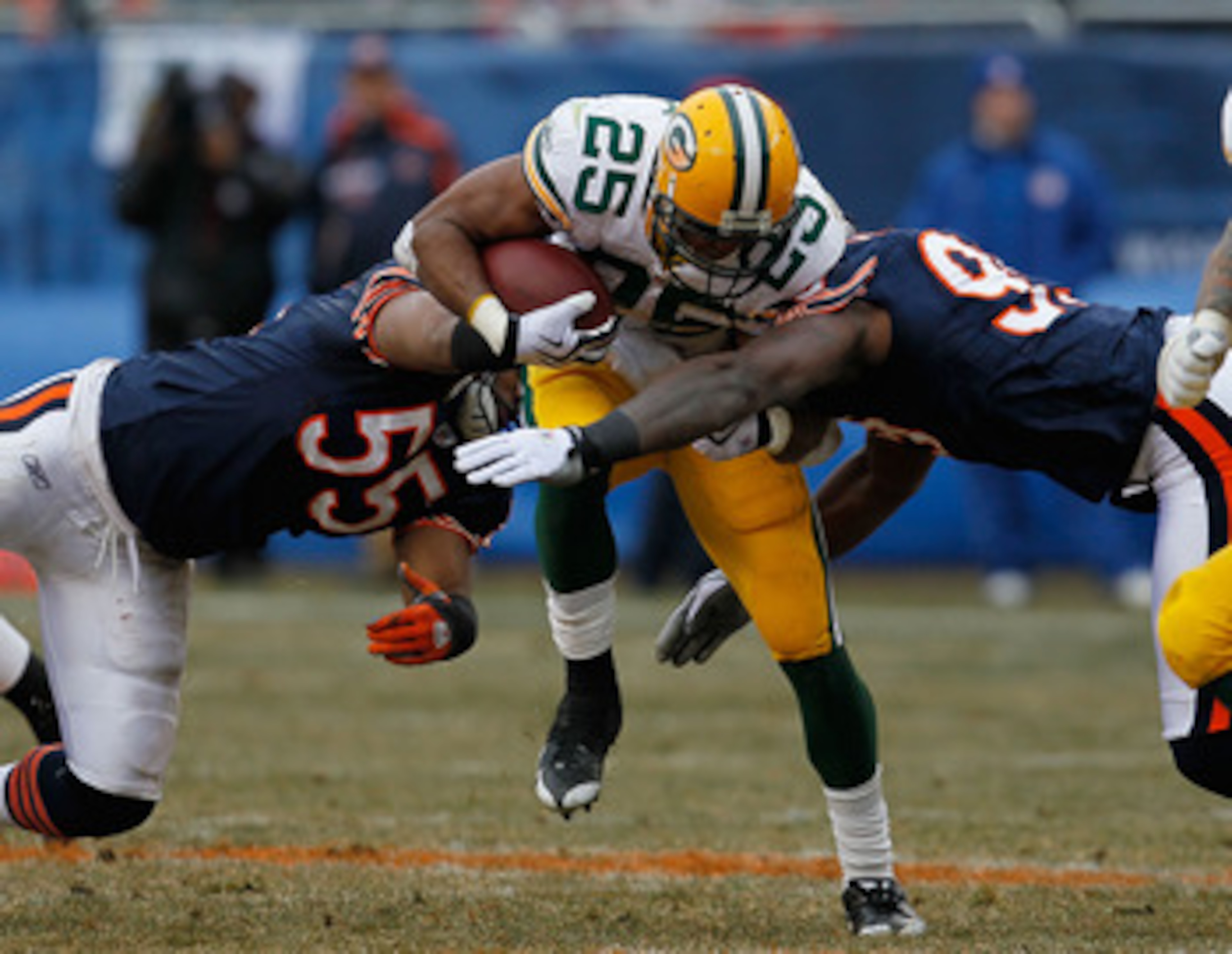 CHICAGO - DECEMBER 13: Ryan Grant #25 of the Green Bay Packers tries to break away from Lance Briggs #55 and Gaines Adams #99 of the Chicago Bears at Soldier Field on December 13, 2009 in Chicago, Illinois. The Packers defeated the Bears 21-14. (Photo by