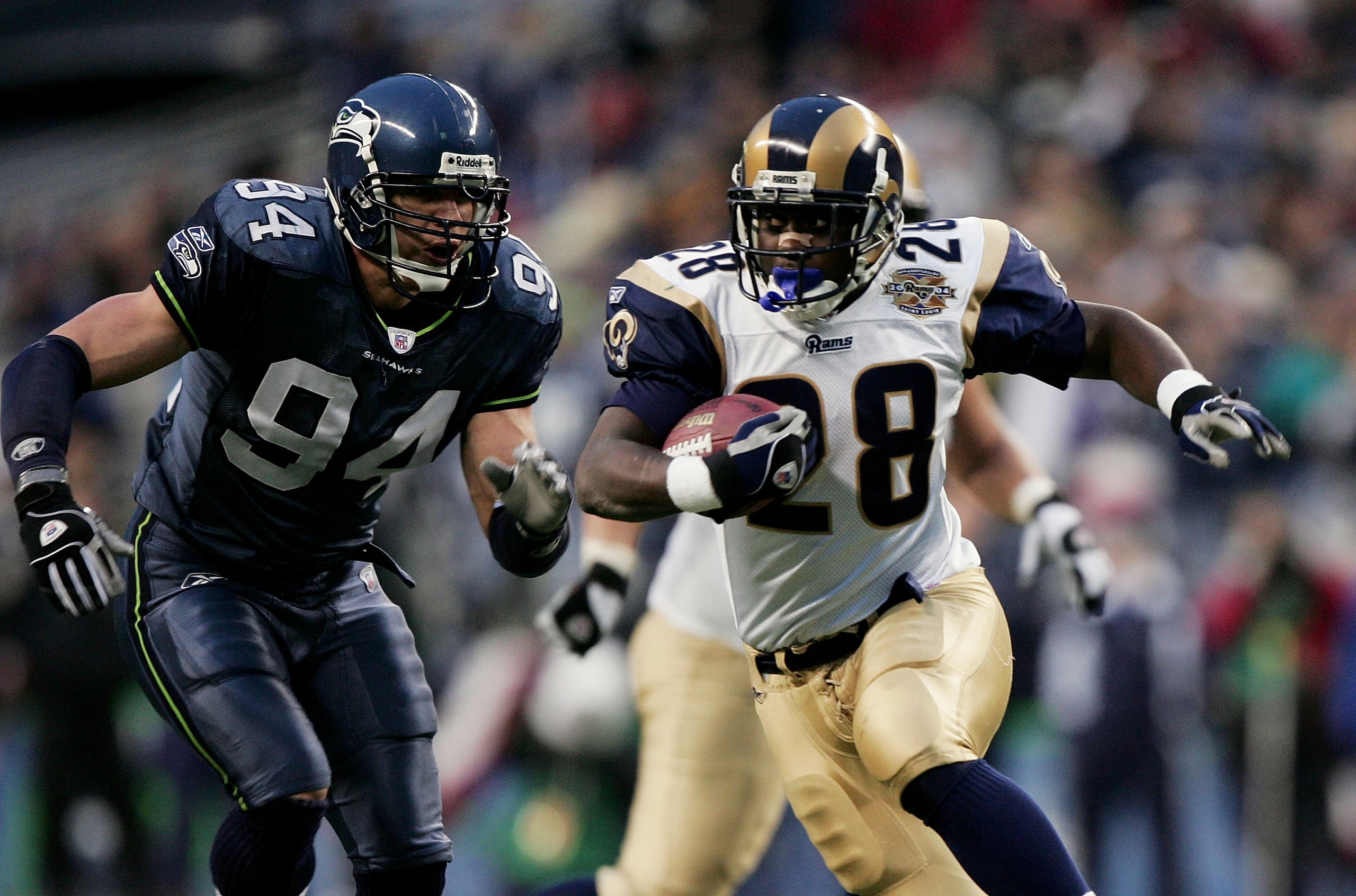 SEATTLE - JANUARY 8:  Running back Marshall Faulk #28 of the St. Louis Rams runs away from linebacker Chad Brown #94 of the Seattle Seahawks in the NFC wild-card game at Qwest Field on January 8, 2005 in Seattle, Washington. The Rams defeated the Seahawks