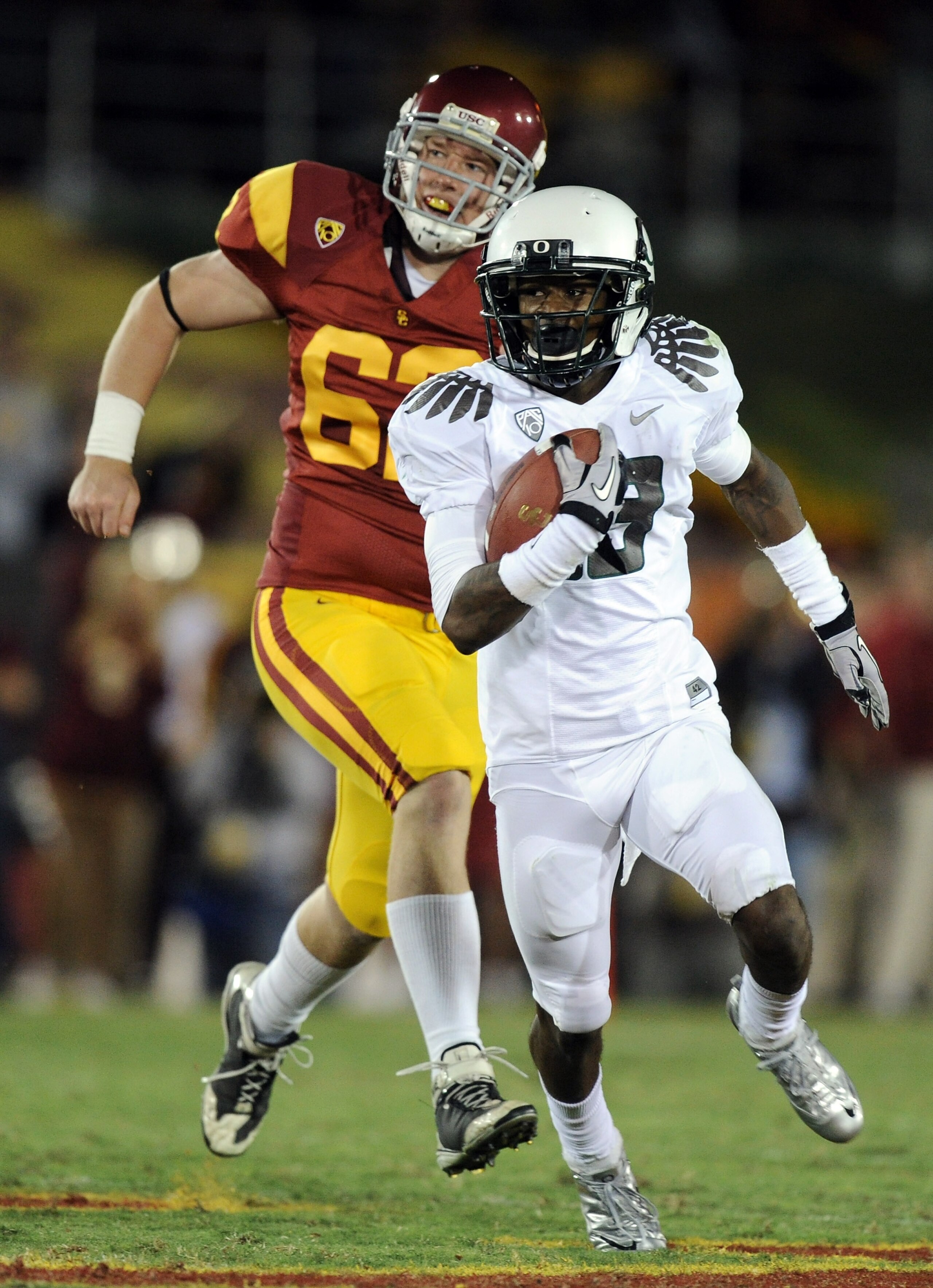 LOS ANGELES, CA - OCTOBER 30:  Cliff Harris #13 of the Oregon Ducks runs past Chris Pousson #62 of the USC Trojans during the second quarter at Los Angeles Memorial Coliseum on October 30, 2010 in Los Angeles, California.  (Photo by Harry How/Getty Images