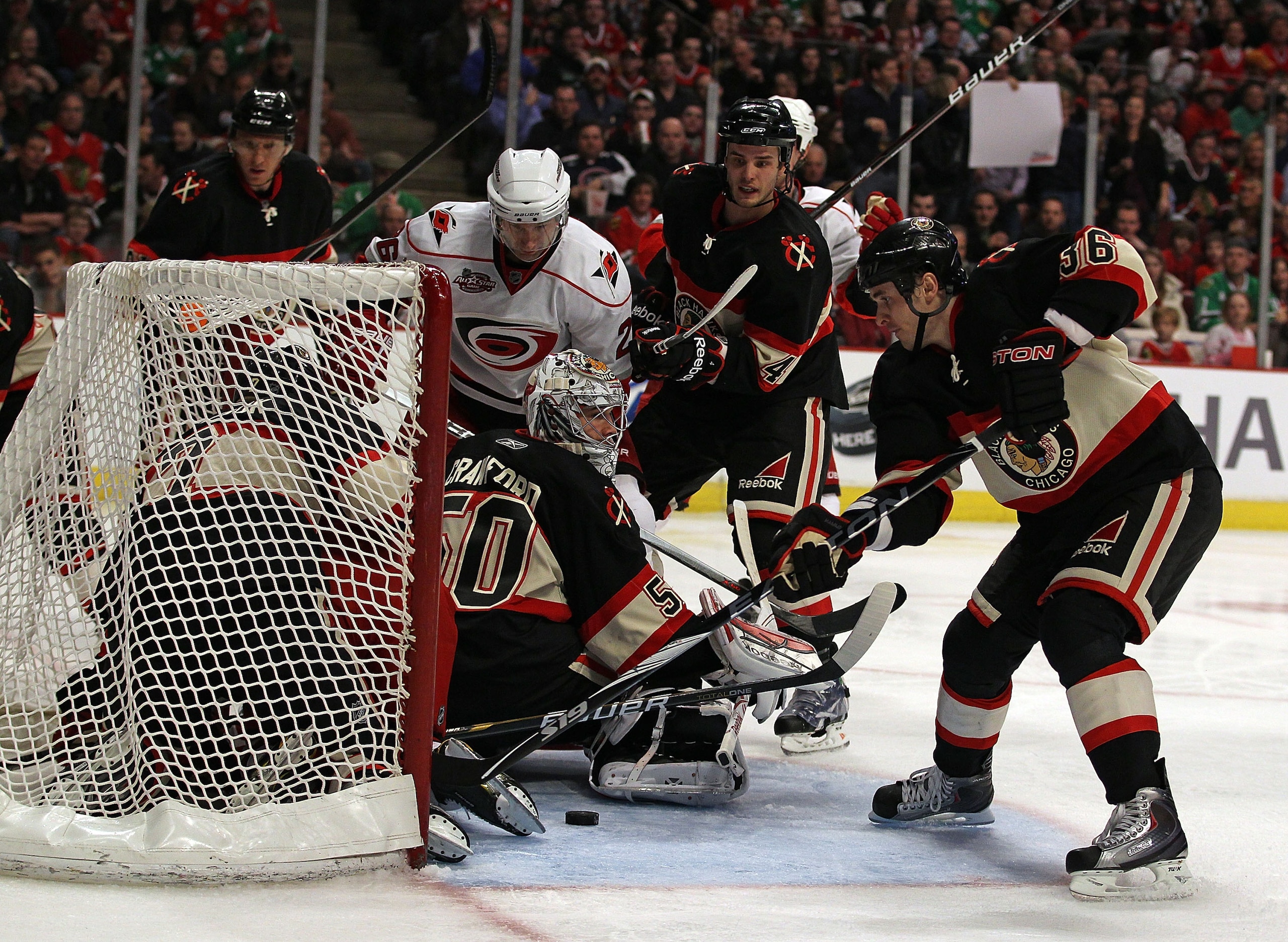 CHICAGO, IL - MARCH 04: Dave Bolland #36 of the Chicago Blackhawks tries to clear the puck after a save by Corey Crawford #50 as teammate Brent Seabrook #7 and Cory Stillman #61 of the Carolina Hurricanes fall into the net at the United Center on March 4,