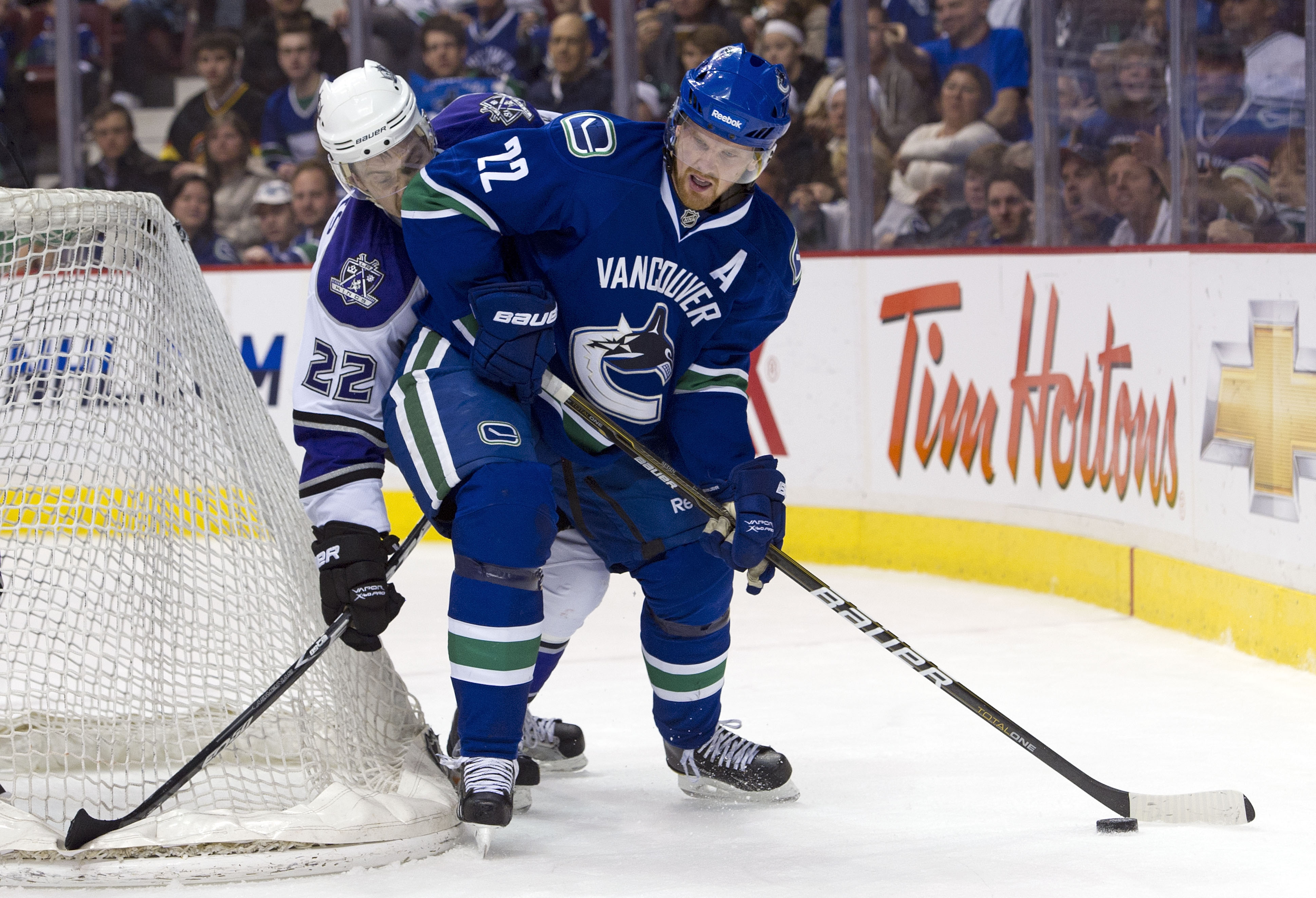 VANCOUVER, CANADA - MARCH 31: Daniel Sedin #22 of the Vancouver Canucks tries to fight off the check of Trevor Lewis #22 of the Los Angeles Kings during the second period in NHL action on March 31, 2011 at Rogers Arena in Vancouver, BC, Canada.  (Photo by