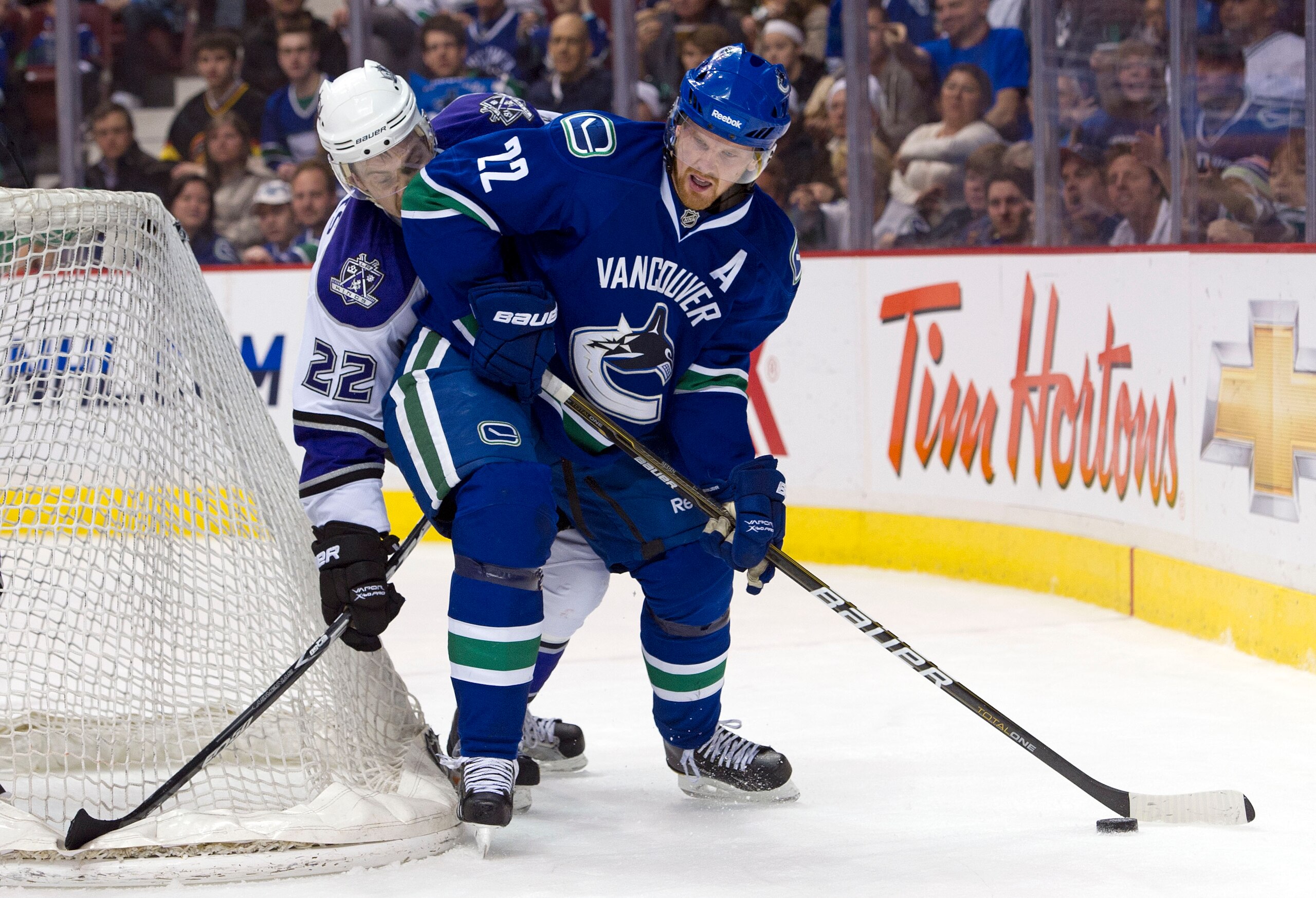VANCOUVER, CANADA - MARCH 31: Daniel Sedin #22 of the Vancouver Canucks tries to fight off the check of Trevor Lewis #22 of the Los Angeles Kings during the second period in NHL action on March 31, 2011 at Rogers Arena in Vancouver, BC, Canada.  (Photo by