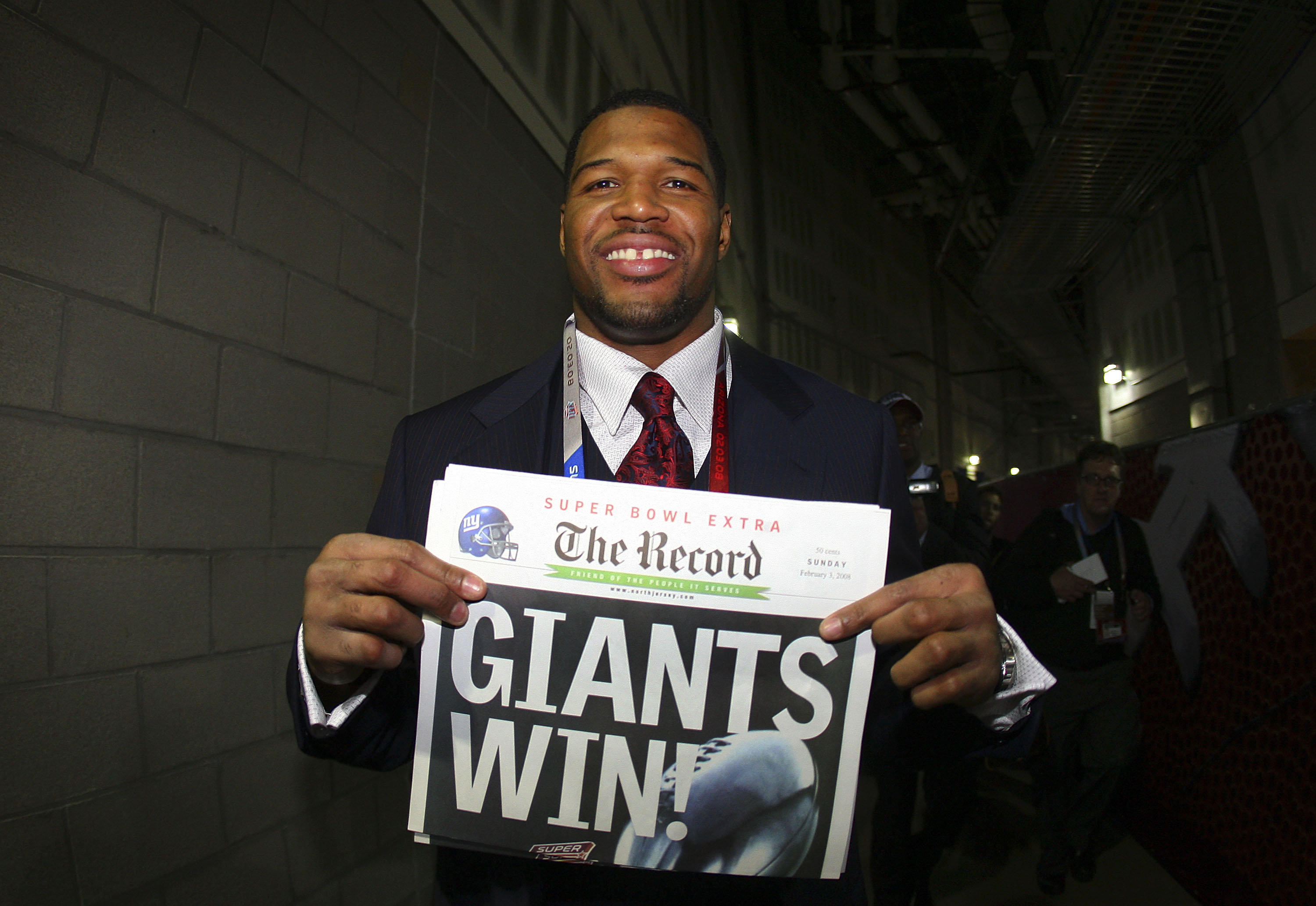 GLENDALE, AZ - FEBRUARY 03:  Defensive end Michael Strahan #92 of the New York Giants holds a newspaper with the headline 'GIANTS WIN!' after the Giants defeated the New England Patriots 17-14 during Super Bowl XLII on February 3, 2008 at the University o