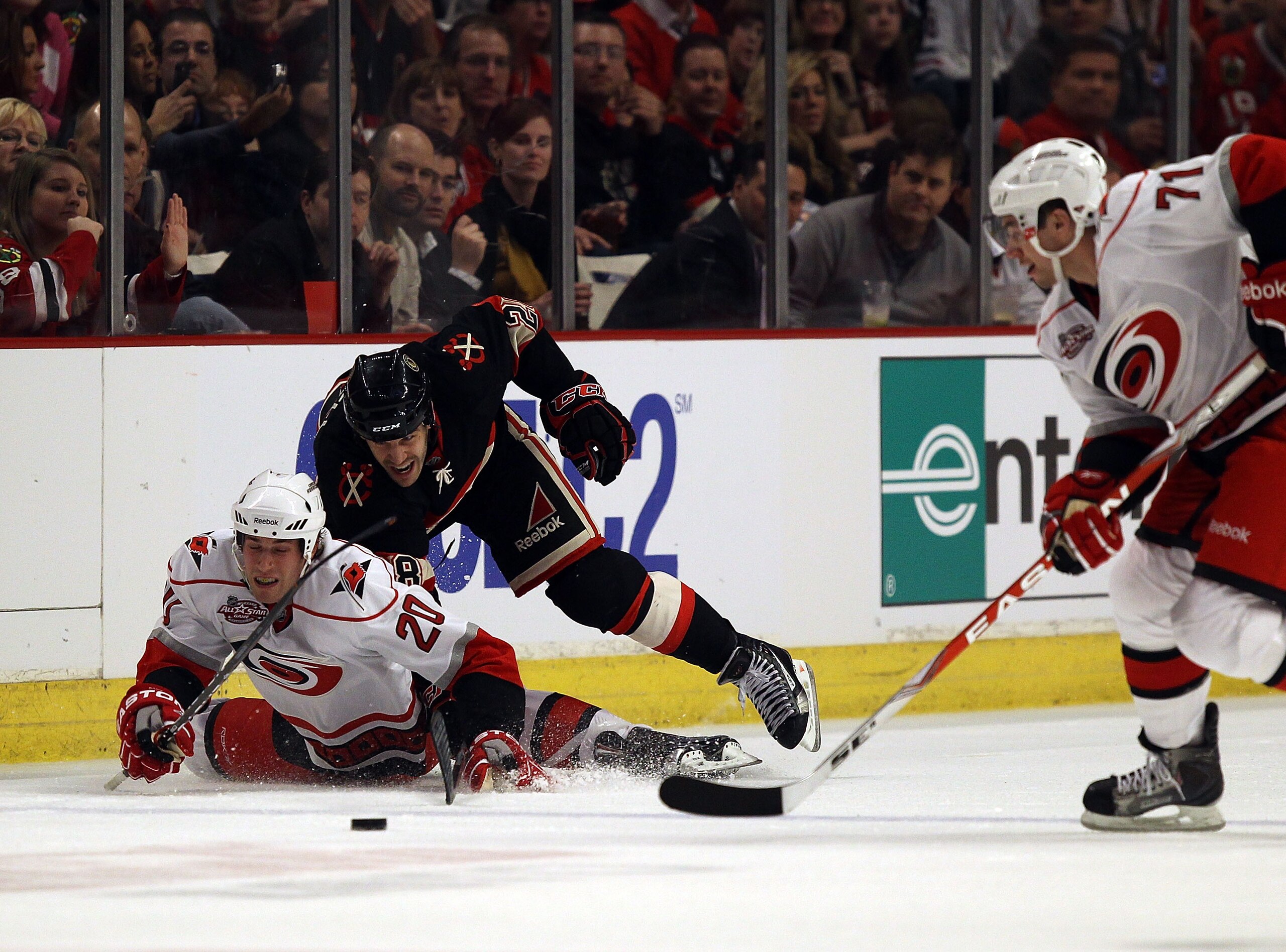 CHICAGO, IL - MARCH 04: Jake Dowell #28 of the Chicago Blackhawks knocks Troy Brodie #20 of the Carolina Hurricanes to the ice as Jerome Samson #71 moves in to take the puck at the United Center on March 4, 2011 in Chicago, Illinois.  (Photo by Jonathan D