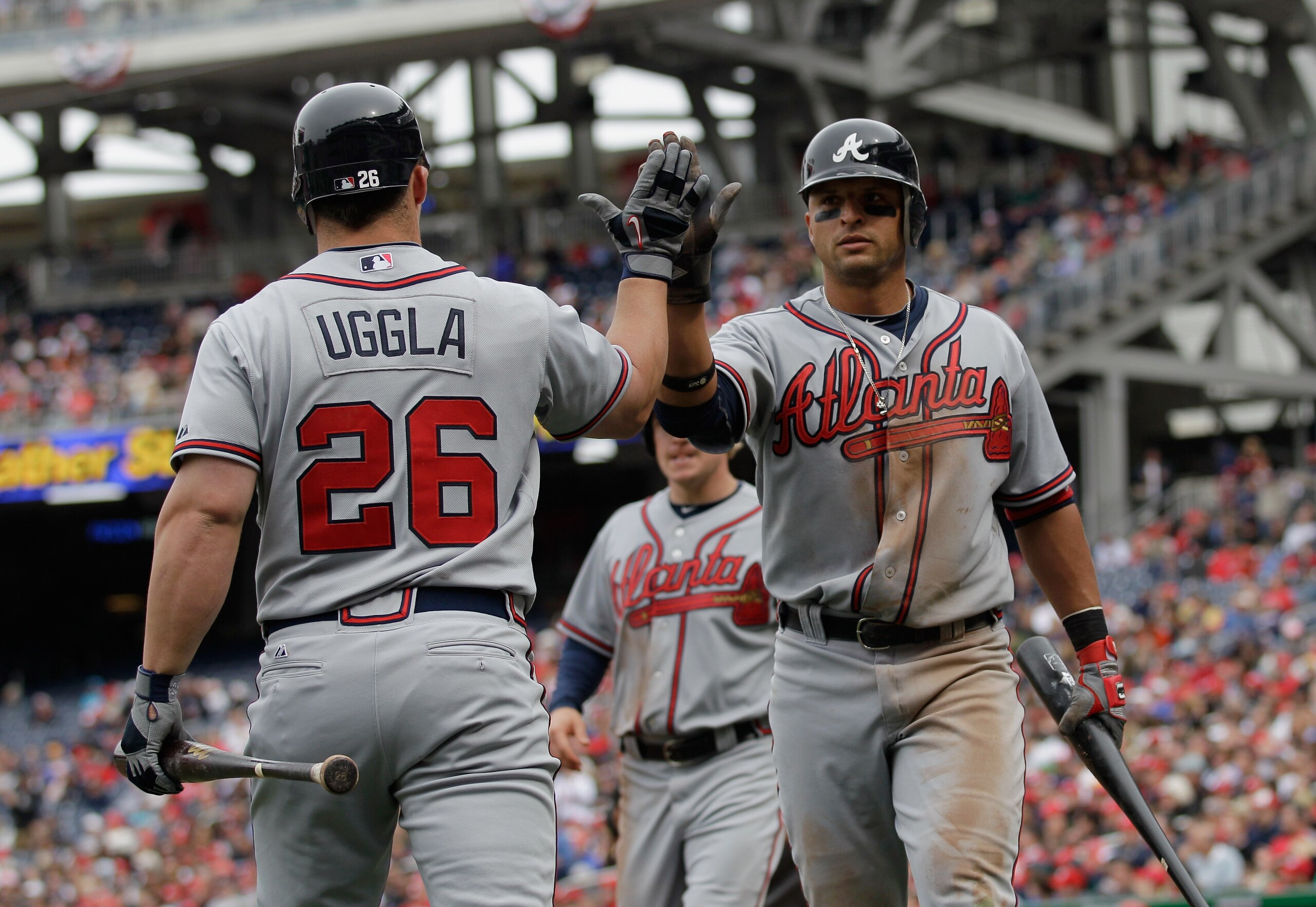 WASHINGTON, DC - APRIL 03: Martin Prado #14 of the Atlanta Braves (R) is congratulated by teammate Dan Uggla #26 after scoring against the Washington Nationals during the seventh inning at Nationals Park on April 3, 2011 in Washington, DC.  (Photo by Rob