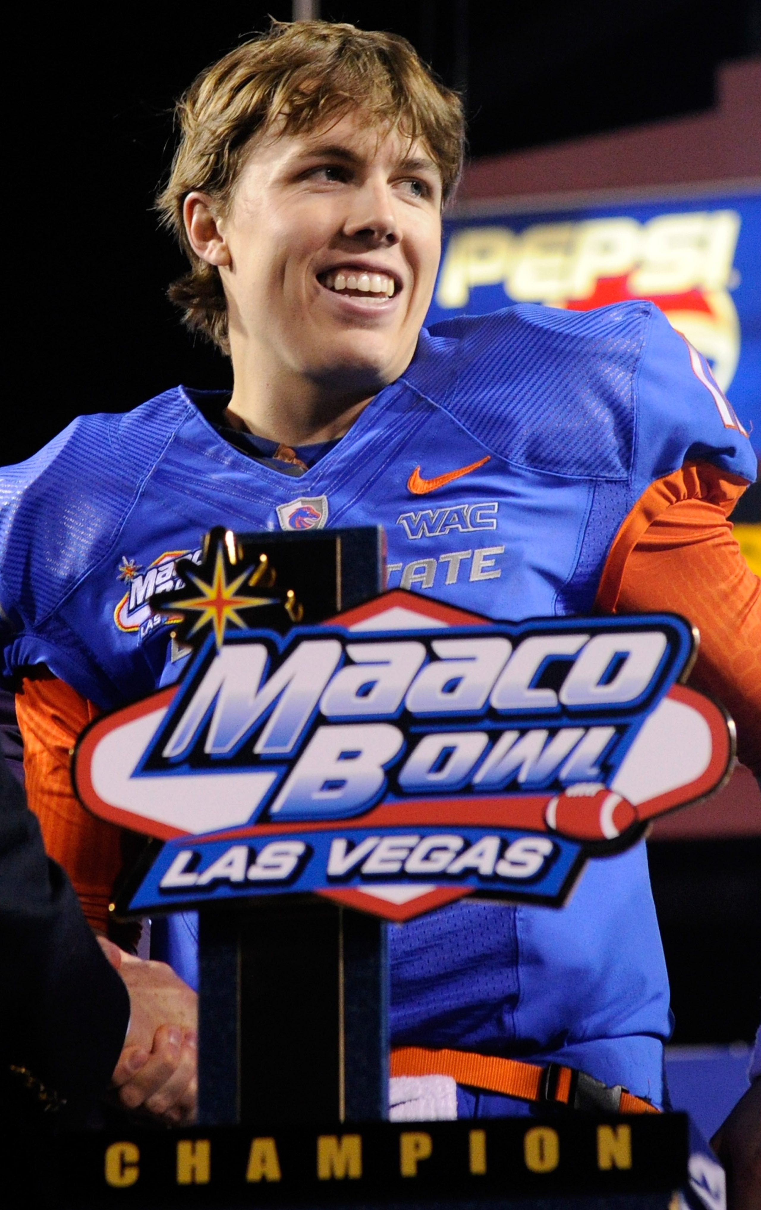 LAS VEGAS, NV - DECEMBER 22: Quarterback Kellen Moore #11 of the Boise State Broncos smiles while standing behind a trophy as he celebrates the team's 26-3 victory over the Utah Utes in the MAACO Bowl Las Vegas at Sam Boyd Stadium December 22, 2010 in La LAS VEGAS, NV - DECEMBER 22: Quarterback Kellen Moore #11 of the Boise State Broncos smiles while standing behind a trophy as he celebrates the team's 26-3 victory over the Utah Utes in the MAACO Bowl Las Vegas at Sam Boyd Stadium December 22, 2010 in La