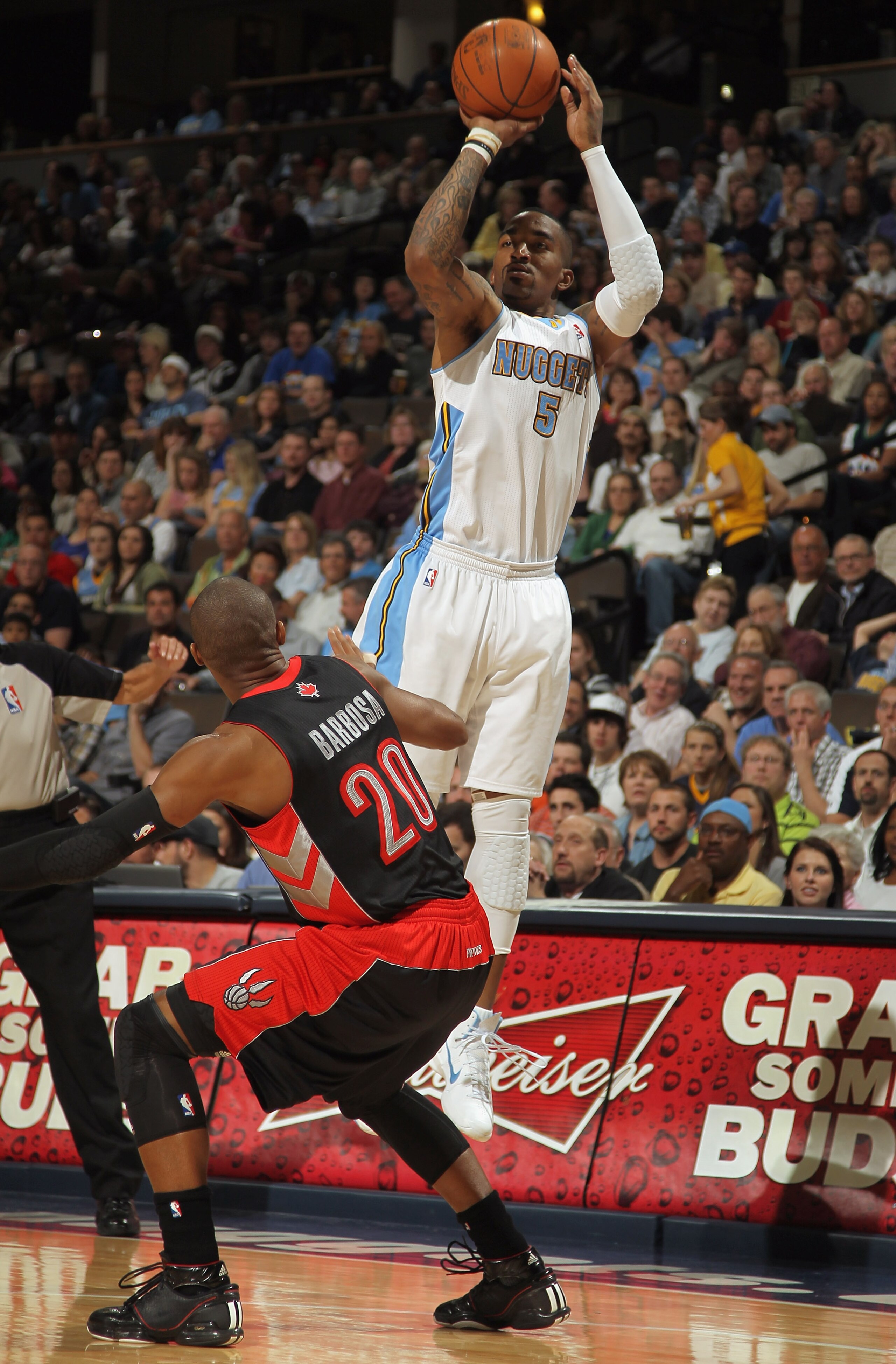DENVER, CO - MARCH 21:  J.R. Smith #5 of the Denver Nuggets takes a shot over Leandro Barbosa #20 of the Toronto Raptors at the Pepsi Center on March 21, 2011 in Denver, Colorado. The Nuggets defeated the Raptors 123-90. NOTE TO USER: User expressly ackno