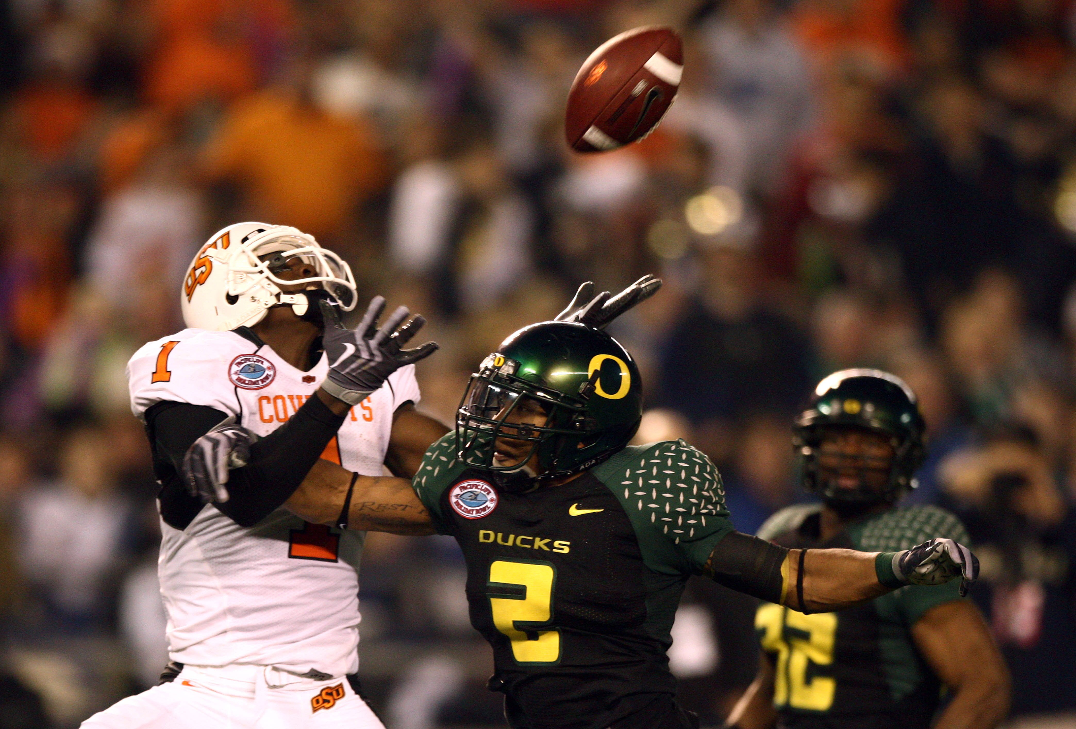 SAN DIEGO, CA - DECEMBER 30:   Wide Receiver Dez Bryant  #1 of the Oklahoma State University Cowboys jumps up to catch the ball as Free Safety T.J. Ward #2 of the University of Oregon Ducks breaks up the pass during the Pacific Life Holiday Bowl at Qualco