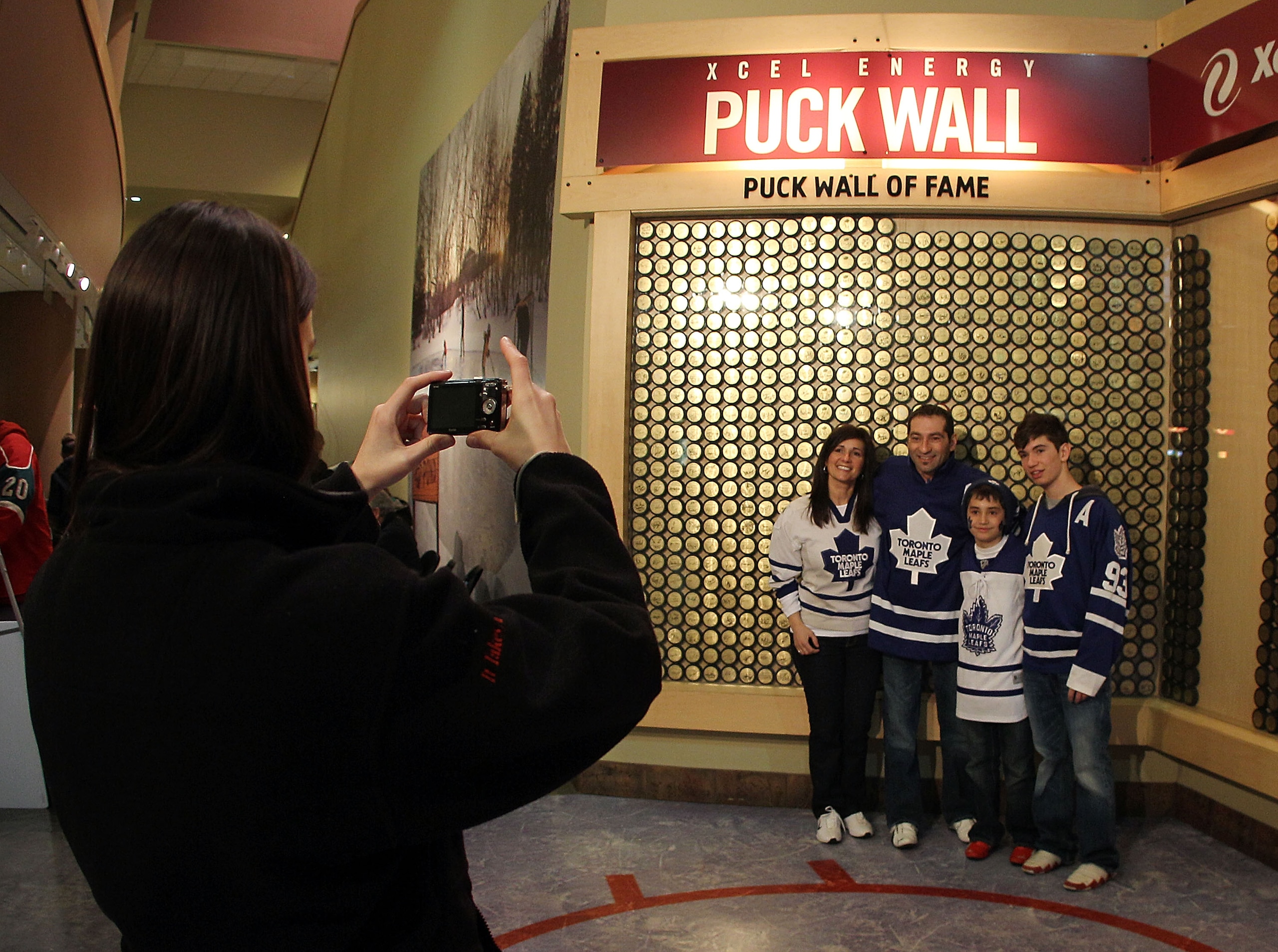 ST PAUL, MN - MARCH 22: Fans pose in front of the puck wall of fame prior to the game between the Minnesota Wild and the Toronto Maple Leafs at the Xcel Energy Center on March 22, 2011 in St Paul, Minnesota. (Photo by Bruce Bennett/Getty Images)