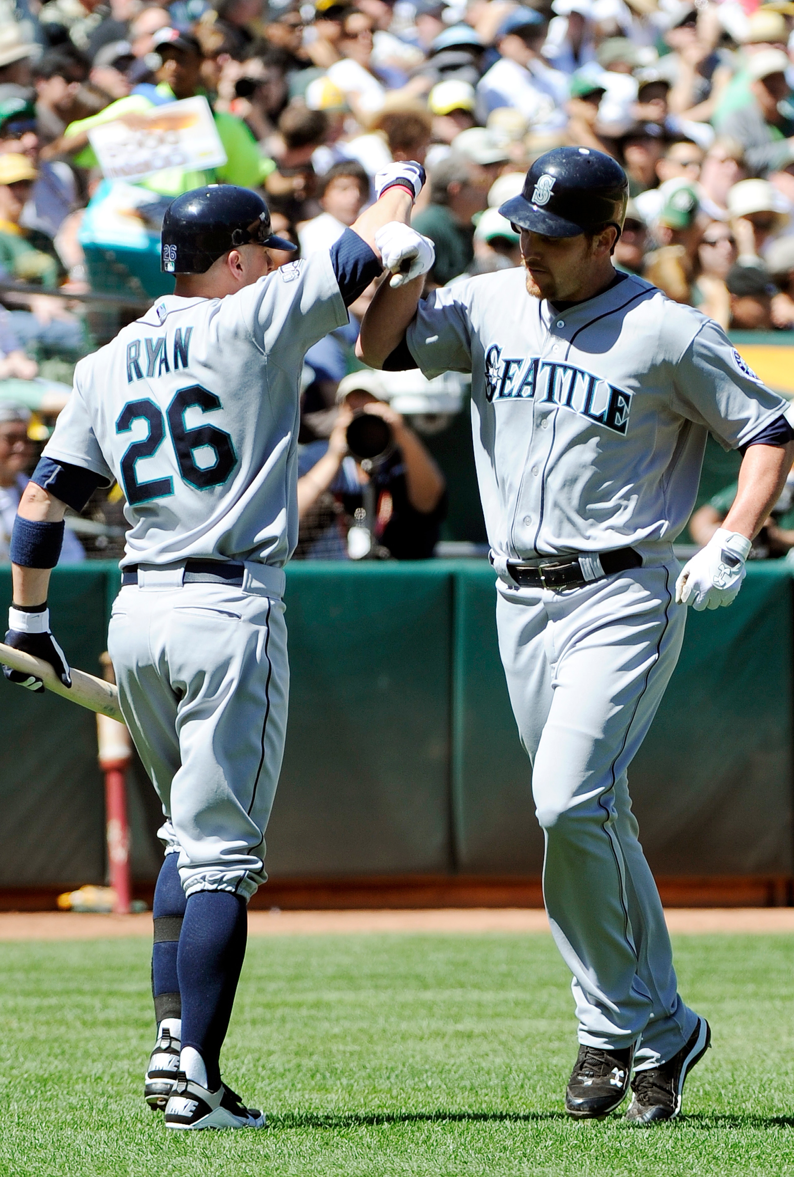 OAKLAND, CA - APRIL 3: Ryan Langerhans #12 of the Seattle Mariners after hitting a home run bashes forearms with teammate Brendan Ryan #26 against the Oakland Athletics during a MLB baseball game at the Oakland-Alameda County Coliseum April 3, 2011 in Oak