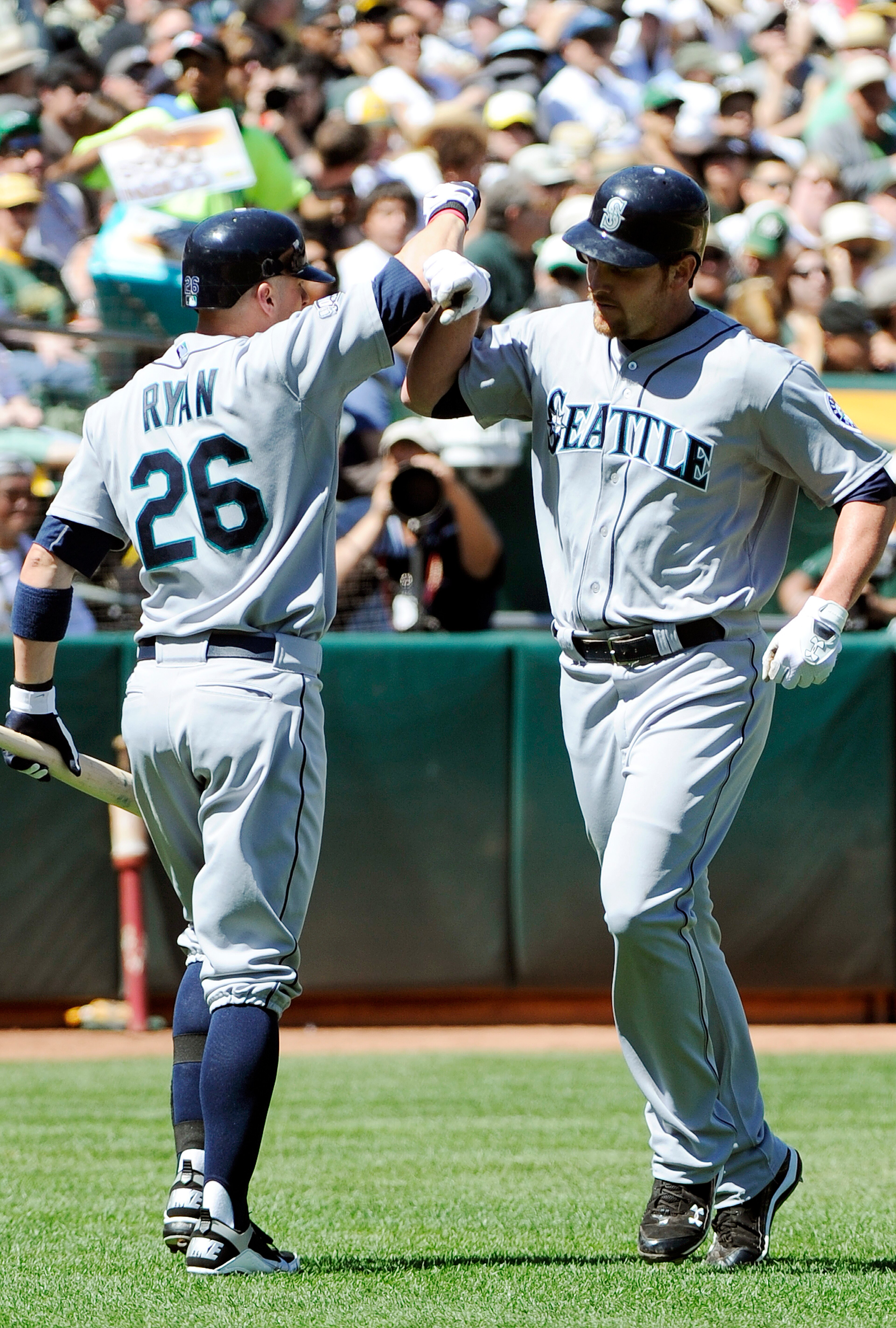 OAKLAND, CA - APRIL 3: Ryan Langerhans #12 of the Seattle Mariners after hitting a home run bashes forearms with teammate Brendan Ryan #26 against the Oakland Athletics during a MLB baseball game at the Oakland-Alameda County Coliseum April 3, 2011 in Oak