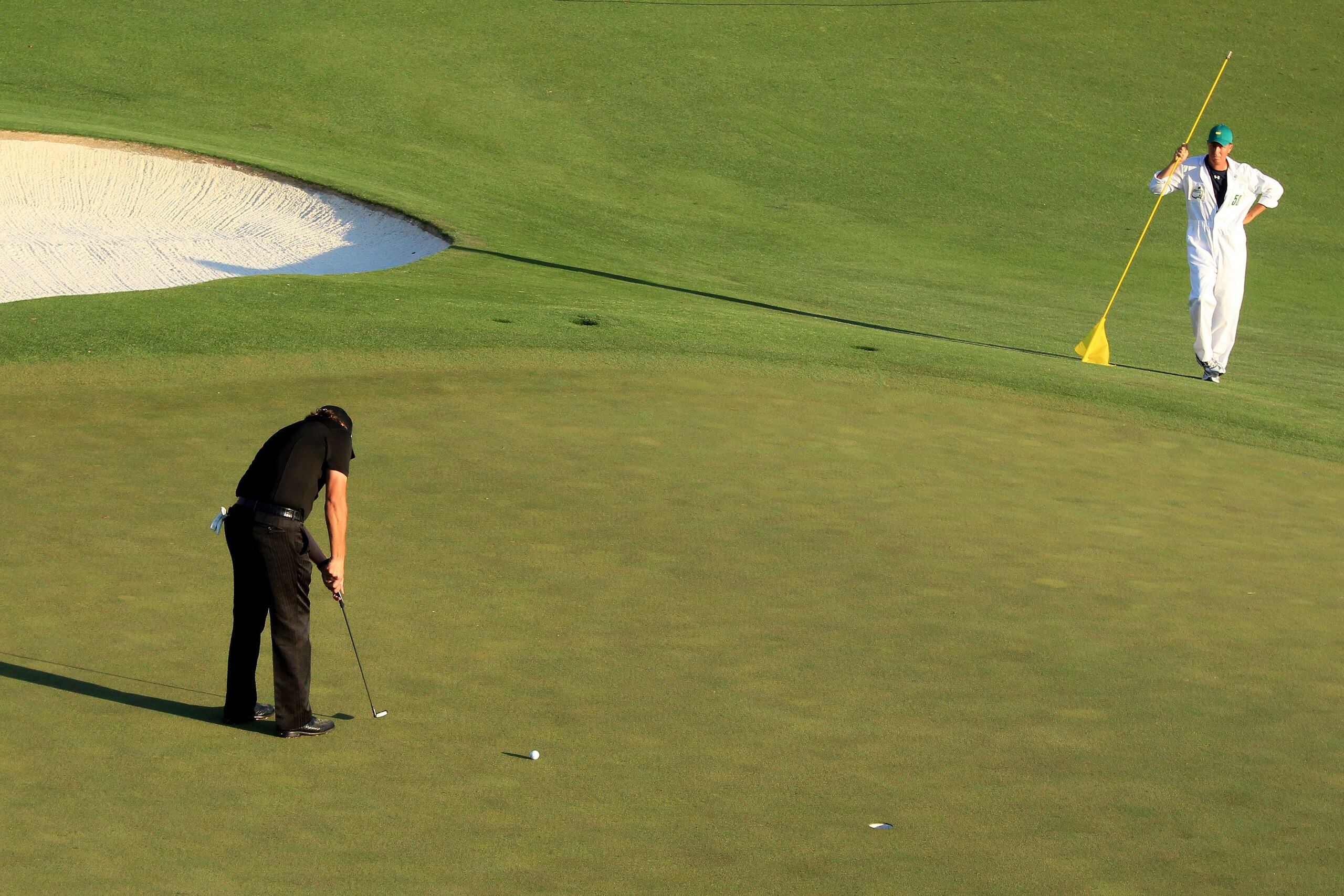 AUGUSTA, GA - APRIL 11:  Phil Mickelson putts for birdie on the 18th green as his caddie Jim Mackay looks on during the final round of the 2010 Masters Tournament at Augusta National Golf Club on April 11, 2010 in Augusta, Georgia.  (Photo by David Cannon