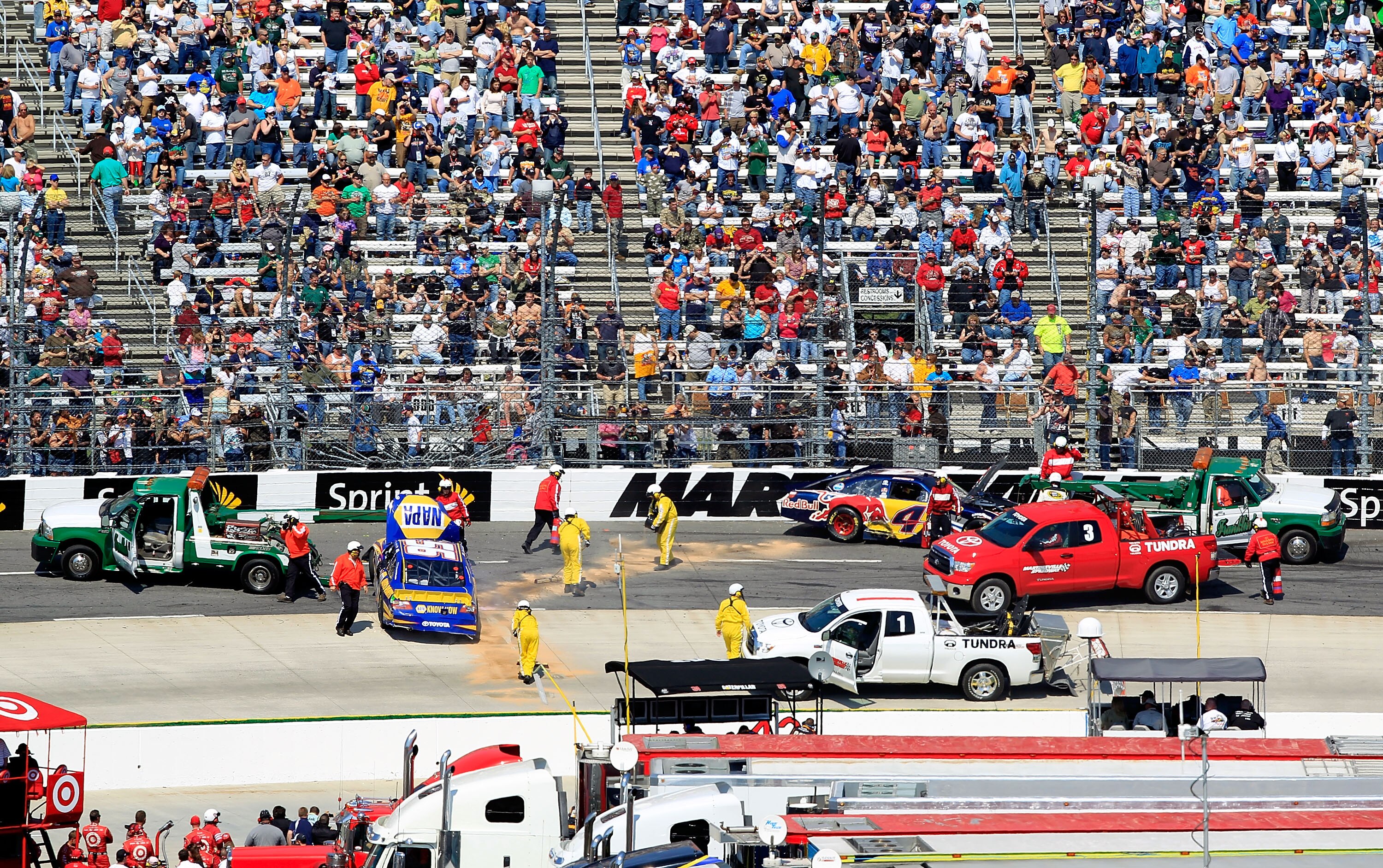MARTINSVILLE, VA - APRIL 03:  Track Safty workers throw down Speedy Dry around the #56 NAPA Auto Parts Toyota, driven by Martin Truex Jr., after it caught fire because of an incident with Kasey Kahne, driver of the #4 Red Bull Toyota, during the NASCAR Sp