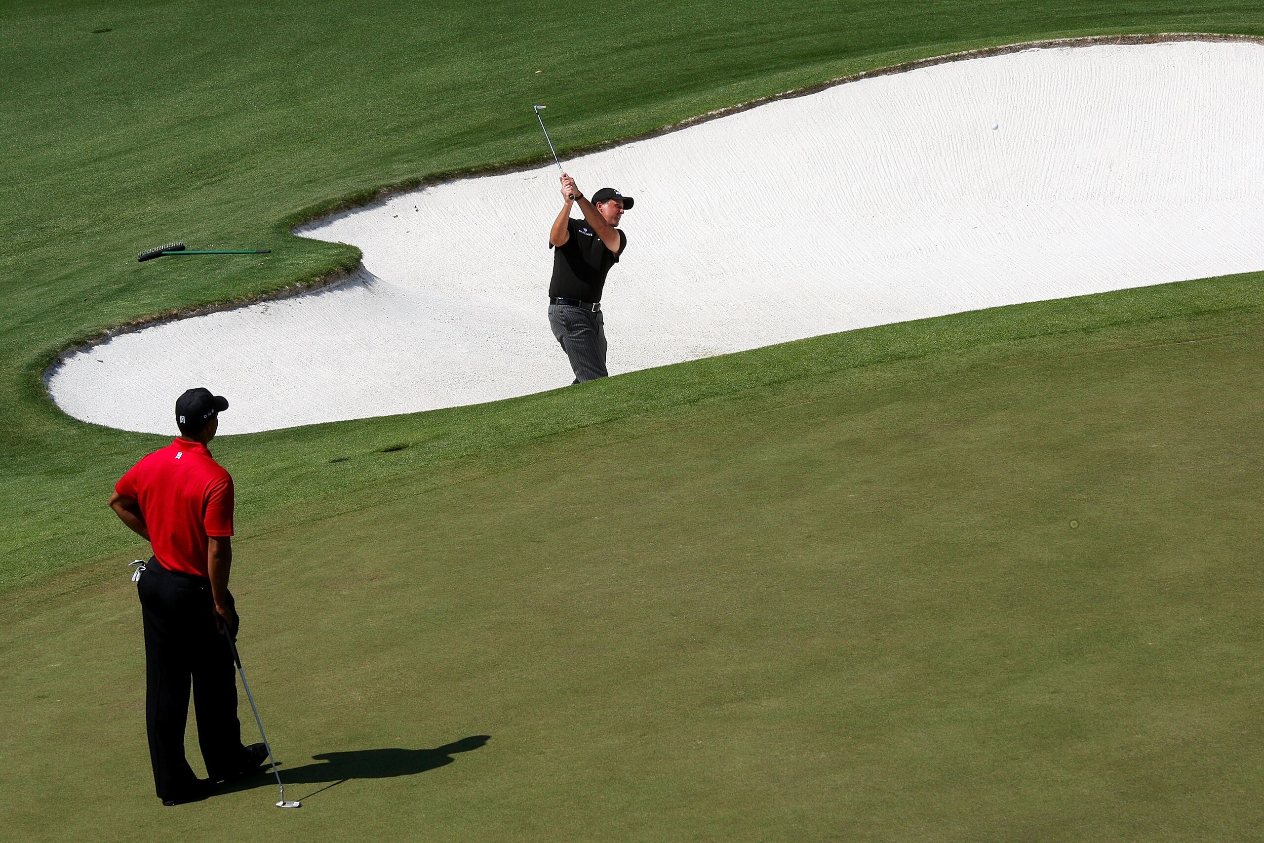 AUGUSTA, GA - APRIL 12: Phil Mickelson plays a bunker shot on the ninth hole as Tiger Woods looks on during the final round of the 2009 Masters Tournament at Augusta National Golf Club on April 12, 2009 in Augusta, Georgia. (Photo by David Cannon/Getty AUGUSTA, GA - APRIL 12: Phil Mickelson plays a bunker shot on the ninth hole as Tiger Woods looks on during the final round of the 2009 Masters Tournament at Augusta National Golf Club on April 12, 2009 in Augusta, Georgia. (Photo by David Cannon/Getty