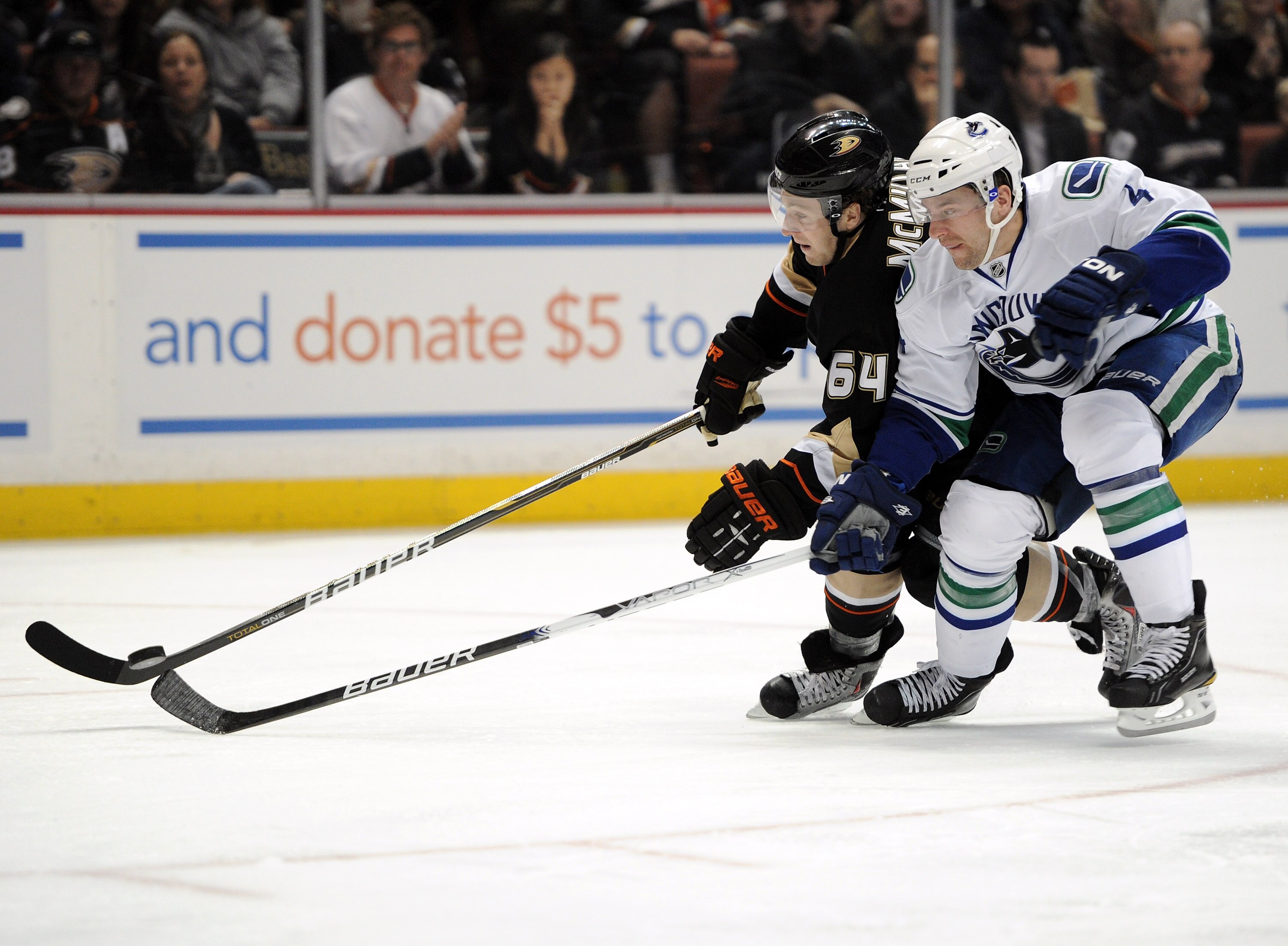 ANAHEIM, CA - MARCH 06:  Keith Ballard #4 of the Vancouver Canucks and Brandon McMillan #64 of the Anaheim Ducks chase after the puck at the Honda Center on March 6, 2011 in Anaheim, California.  (Photo by Harry How/Getty Images)