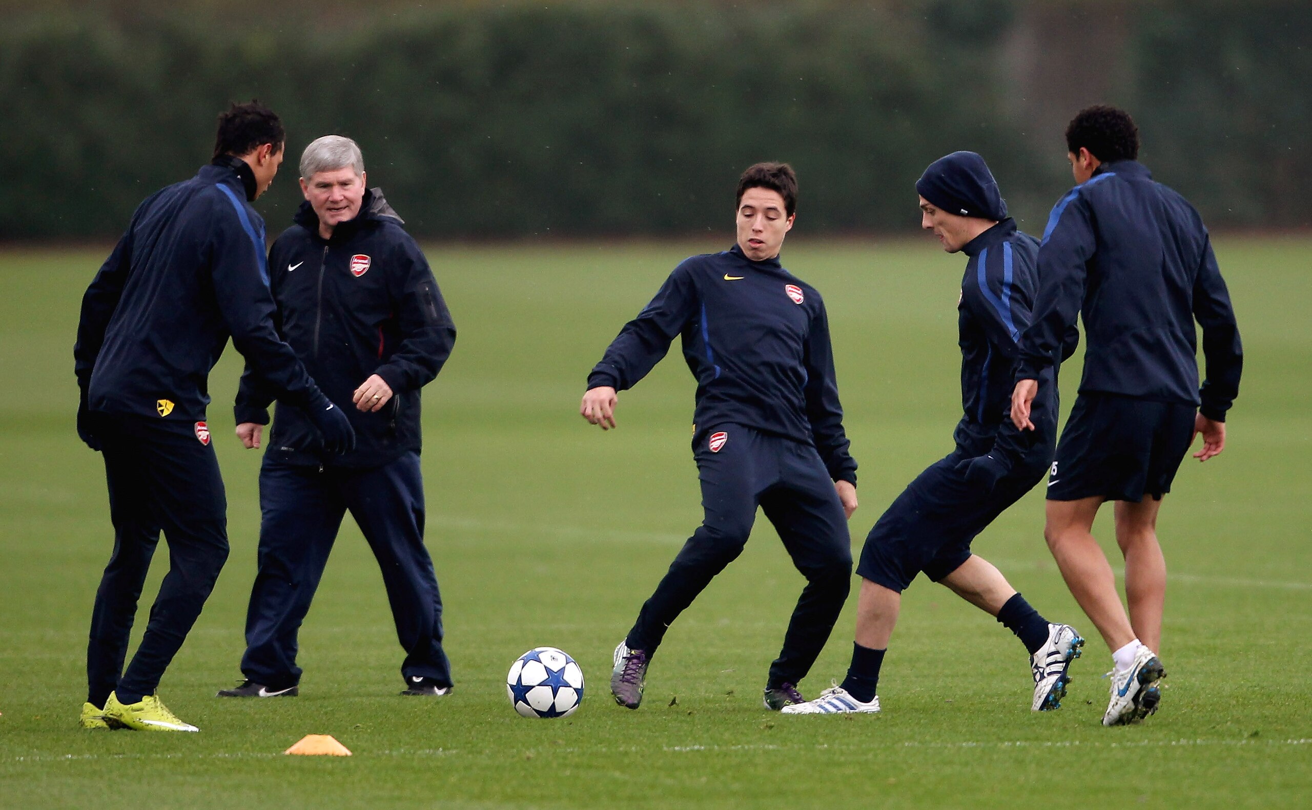 ST ALBANS, ENGLAND - NOVEMBER 22: Samir Nasri (C) is watched by Assistant coach Pat Rice during Arsenal training ahead of their UEFA Champions League match against Braga at London Colney on November 22, 2010 in St Albans, England.  (Photo by Scott Heavey/