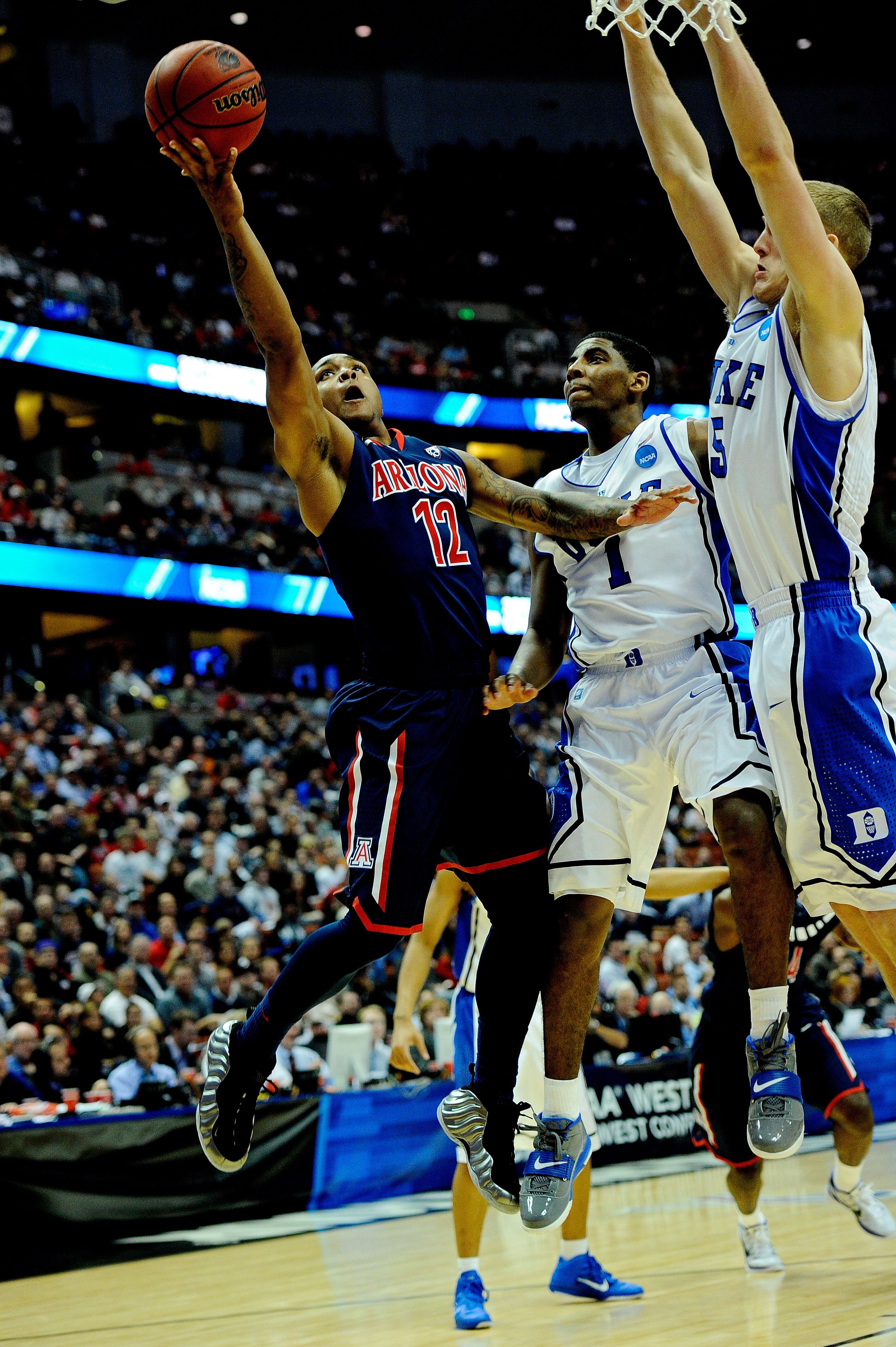 ANAHEIM, CA - MARCH 24:  Lamont Jones #12 of the Arizona Wildcats goes to the hoop against Kyrie Irving #1 and Mason Plumlee #5 of the Duke Blue Devils during the west regional semifinal of the 2011 NCAA men's basketball tournament at the Honda Center on