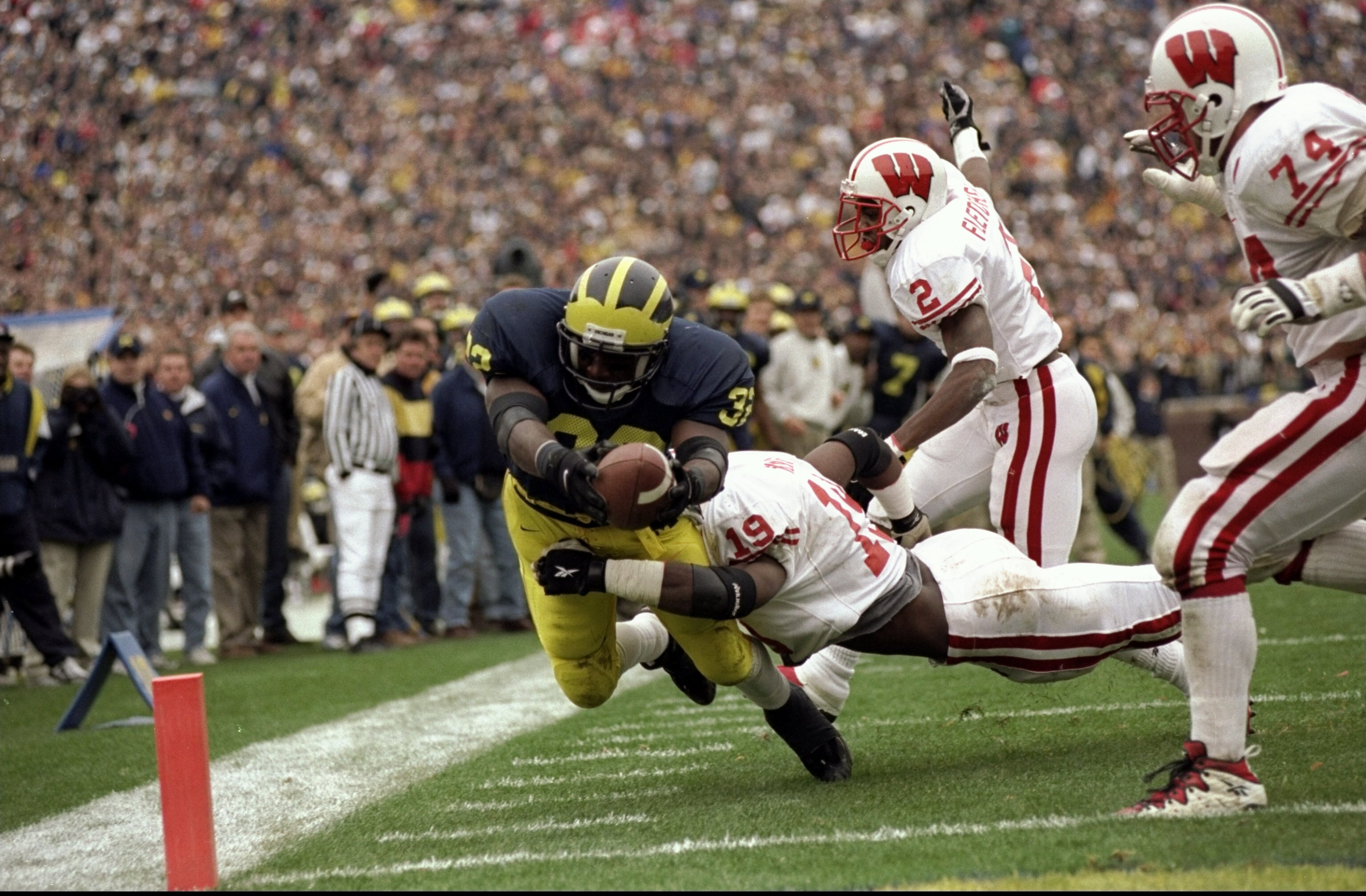 14 Nov 1998:  Tailback Anthony Thomas #32 of the Michigan Wolverines dives across the goal line with the ball while being tackled by Roger Knight #19 of the Wisconsin Badgers during a game at the Michigan Stadium in Ann Arbor, Michigan. The Wolverines def