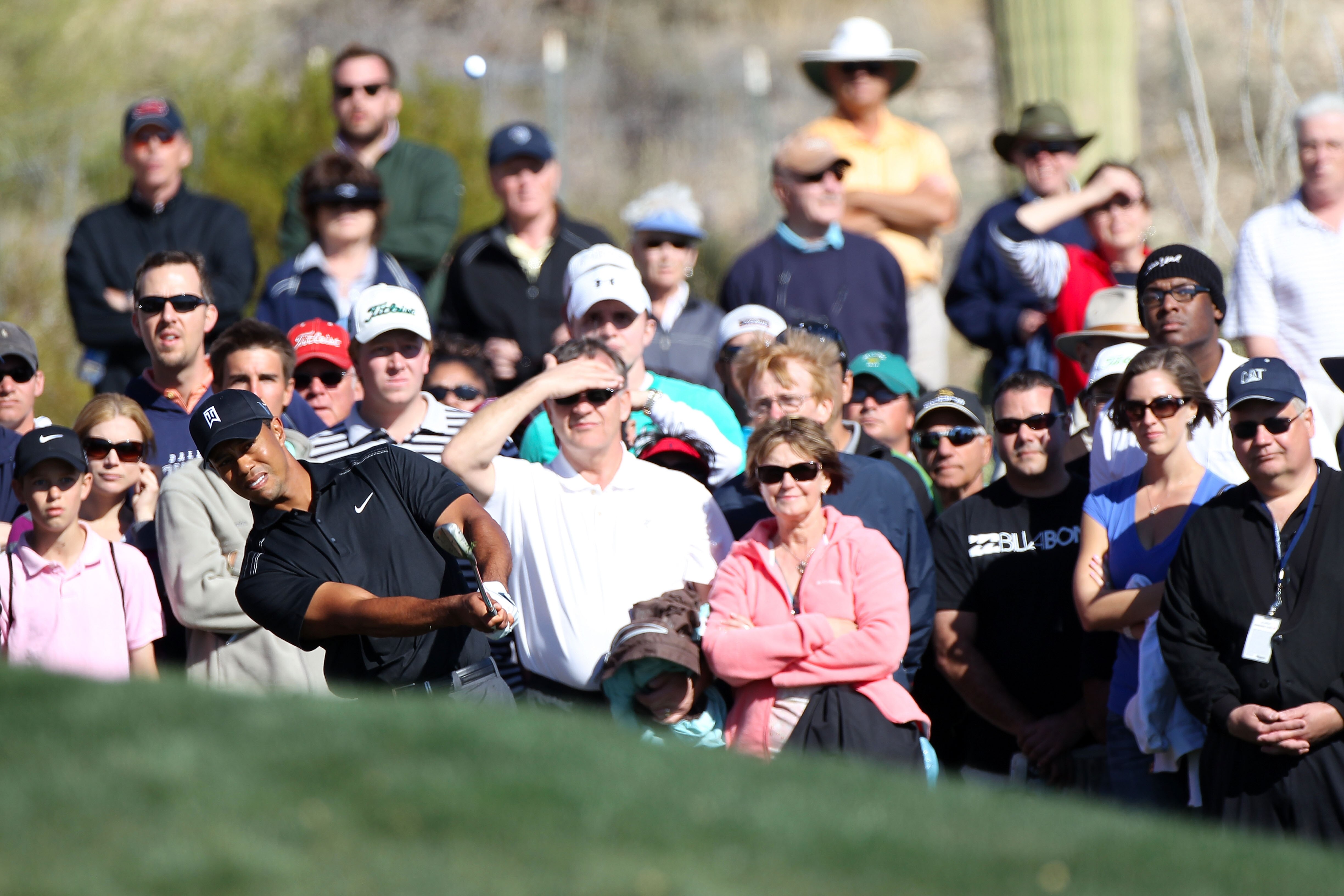 MARANA, AZ - FEBRUARY 23:  Tiger Woods hits an approach shot on the 15th hole as a gallery of fans looks on during the first round of the Accenture Match Play Championship at the Ritz-Carlton Golf Club on February 23, 2011 in Marana, Arizona.  (Photo by S