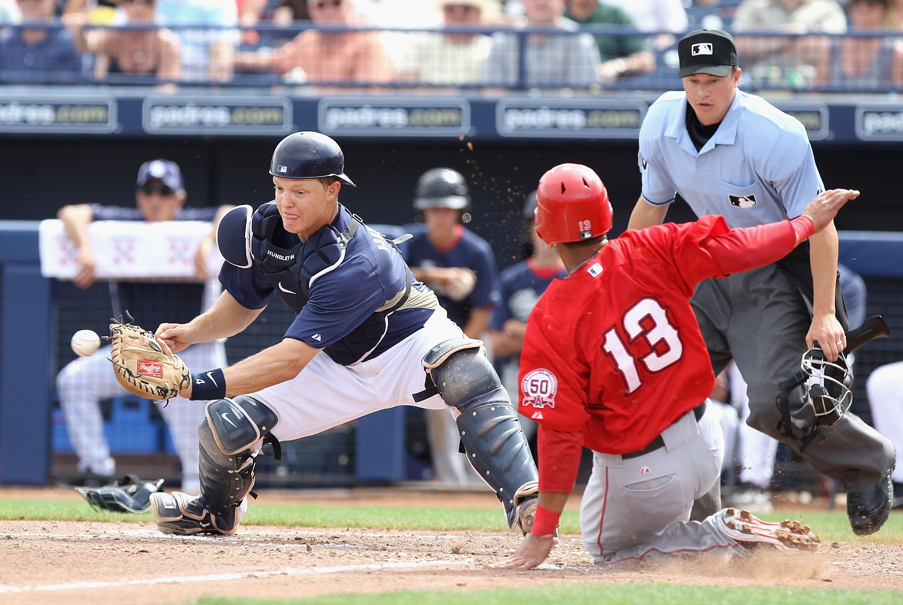 PEORIA, AZ - MARCH 15:  Maicer Izturis #13 of the Los Angeles Angels of Anaheim safely slides into home plate past the tag from catcher Nick Hundley #4 of the San Diego Padres during the third inning of the spring training game at Peoria Stadium on March