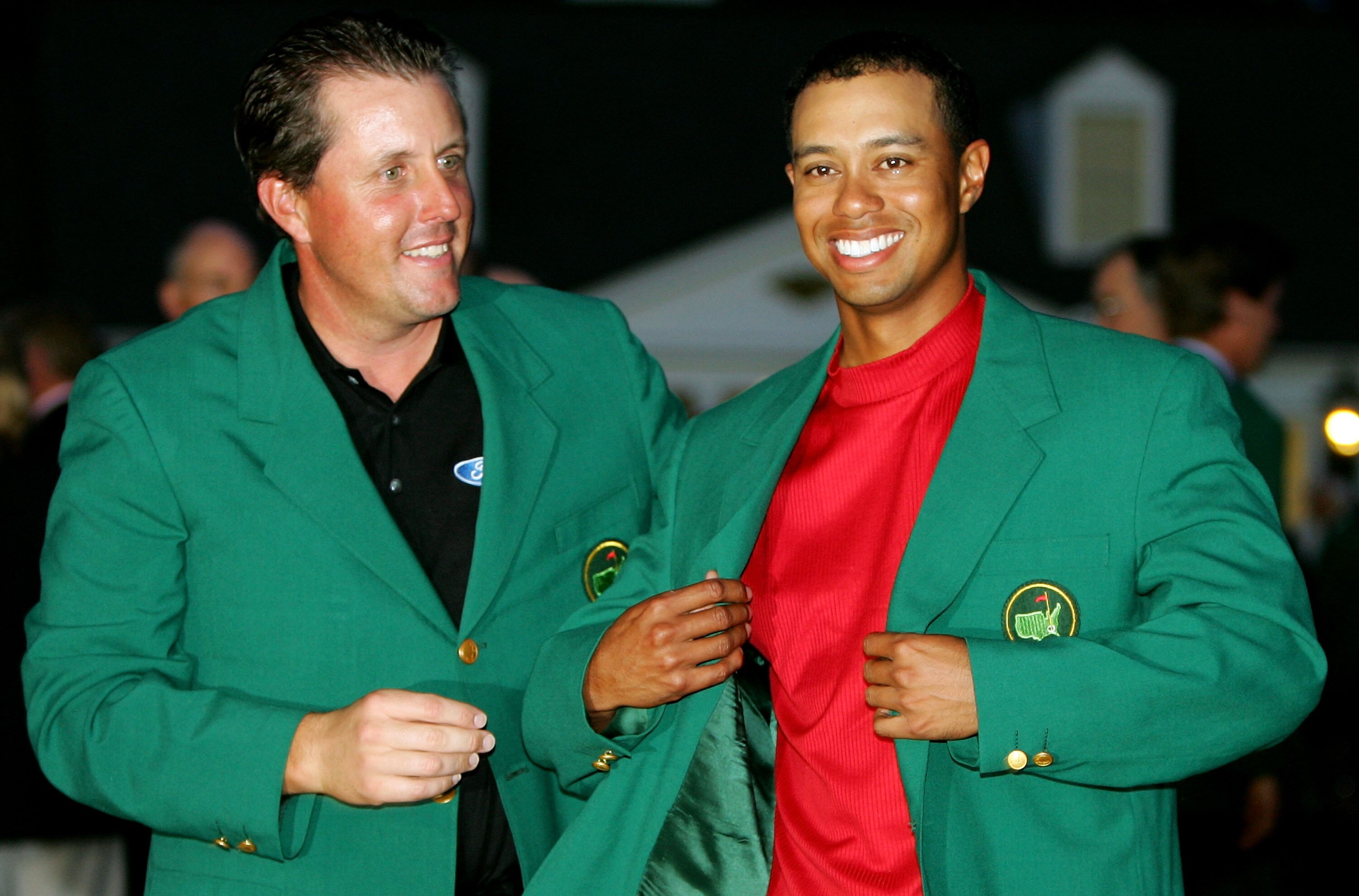 AUGUSTA, GA - APRIL 10:  Tiger Woods smiles as he is presented with the green jacket by Phil Mickelson after Woods won The Masters at the Augusta National Golf Club on April 10, 2005 in Augusta, Georgia.  (Photo by David Cannon/Getty Images)