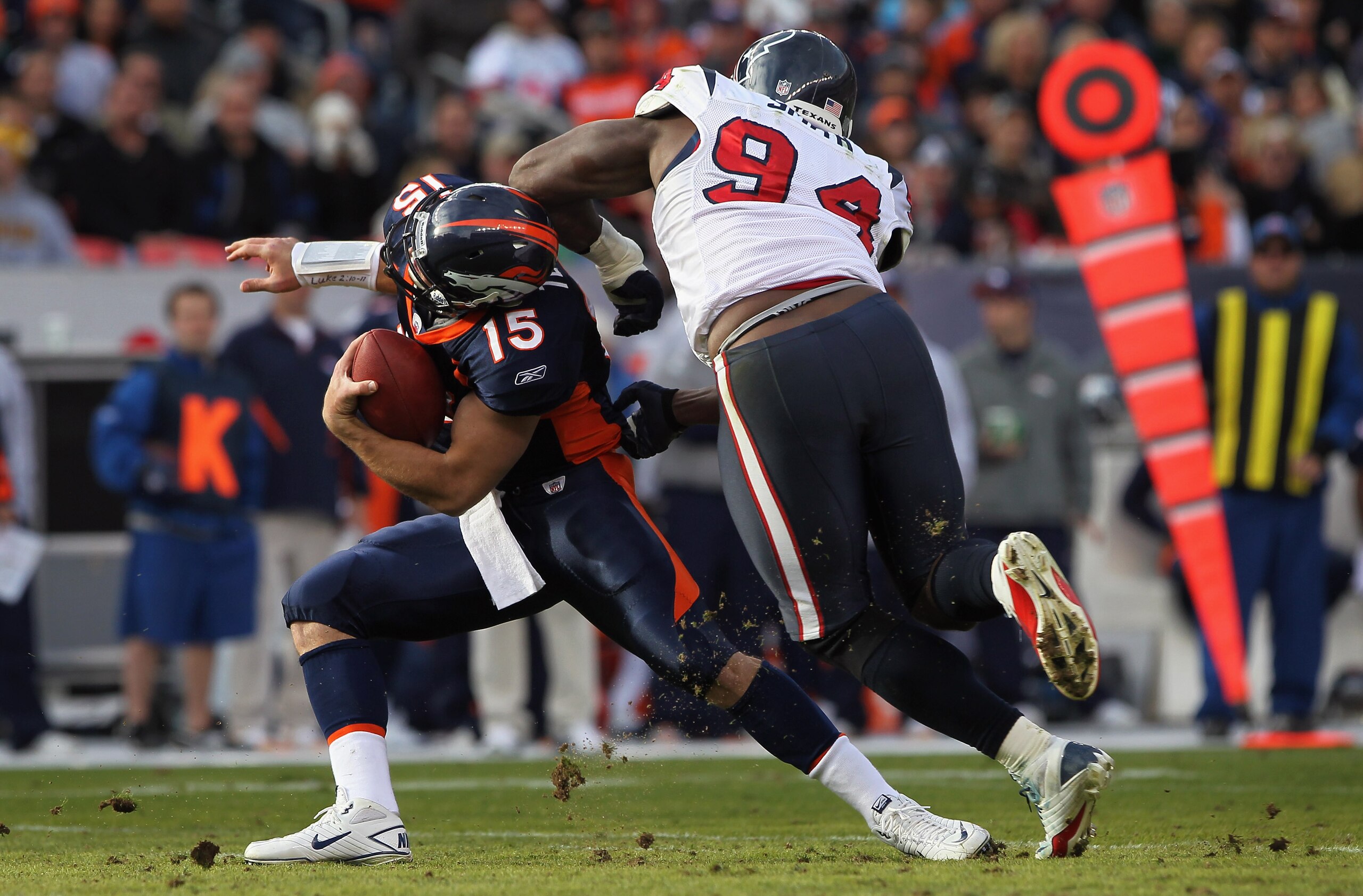 DENVER - DECEMBER 26: Quarterback Tim Tebow #15 of the Denver Broncos eludes a sack attempt by defensive end Antonio Smith #94 of the Houston Texas at INVESCO Field at Mile High on December 26, 2010 in Denver, Colorado. (Photo by Doug Pensinger/Getty Im DENVER - DECEMBER 26: Quarterback Tim Tebow #15 of the Denver Broncos eludes a sack attempt by defensive end Antonio Smith #94 of the Houston Texas at INVESCO Field at Mile High on December 26, 2010 in Denver, Colorado. (Photo by Doug Pensinger/Getty Im