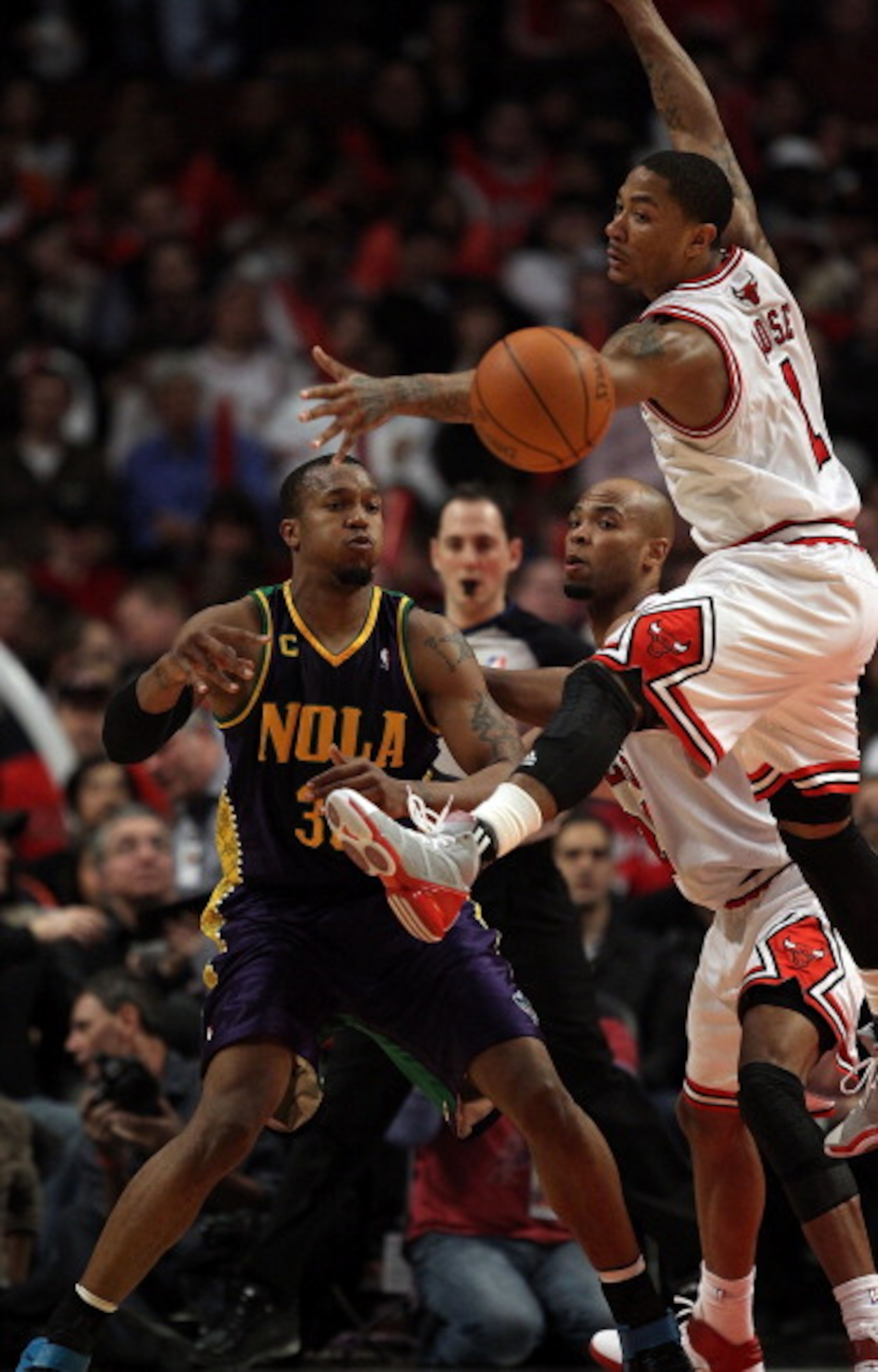 CHICAGO, IL - MARCH 07: David West #30 of the New Orleans Hornets passes the ball as Derrick Rose #1 of the Chicago Bulls leaps to try for the block at the United Center on March 7, 2011 in Chicago, Illinois. The Bulls defeated the Hornets 85-77. NOTE TO