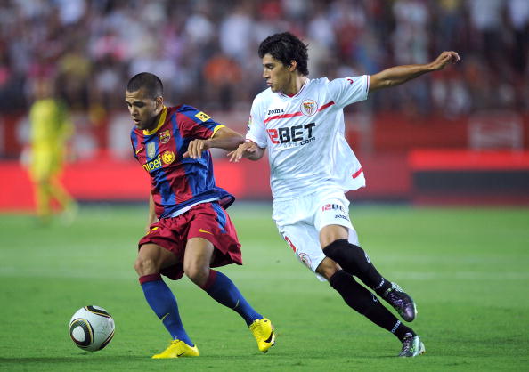 SEVILLE, SPAIN - AUGUST 14: Daniel Alves (L) of Barcelona is challenged by Diego Perotti of Sevilla during the Supercopa, first leg, match between Sevilla and Barcelona at the Sanchez Pizjuan stadium on August 14, 2010 in Seville, Spain. (Photo by Denis D