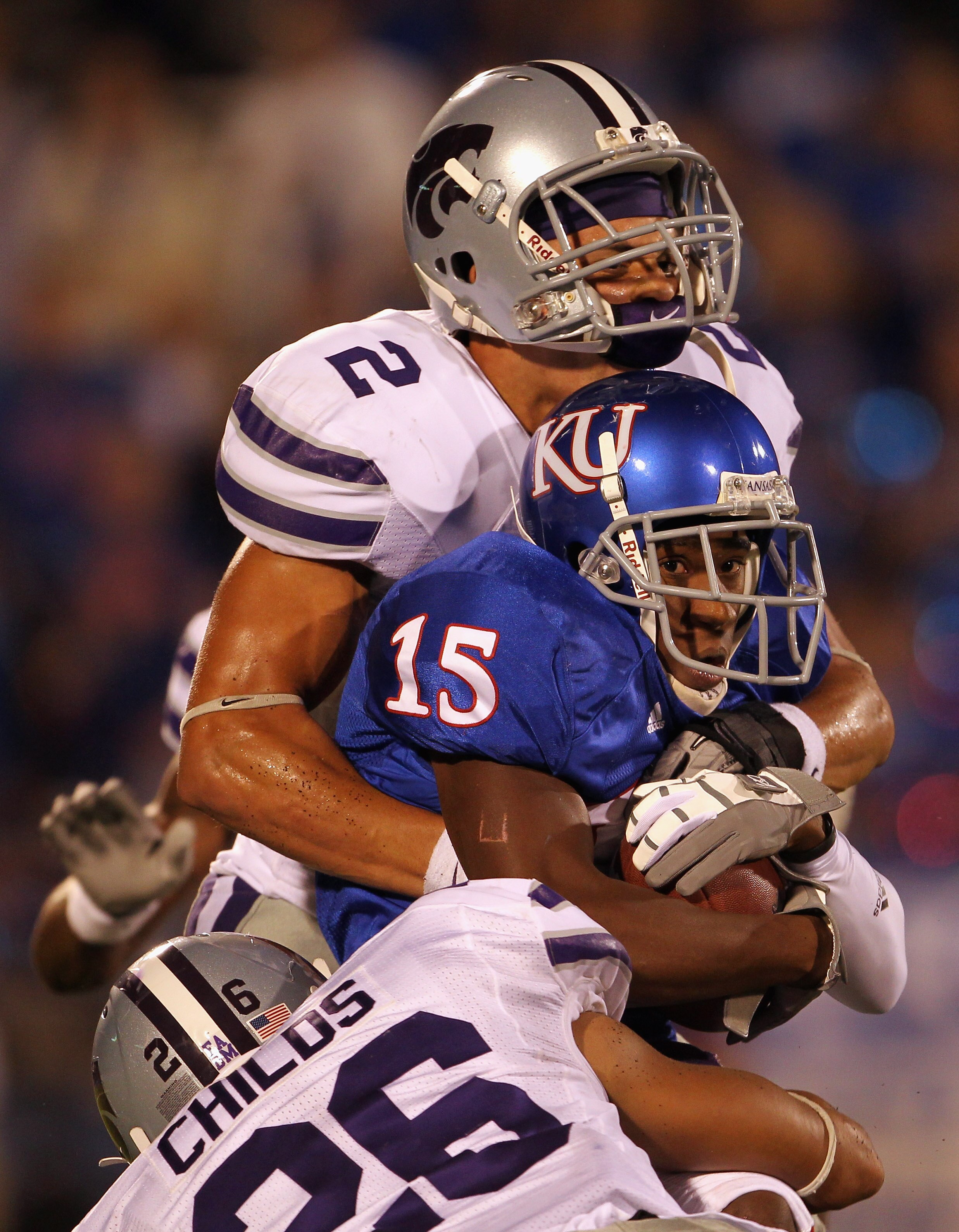 LAWRENCE, KS - OCTOBER 14:  Receiver Daymond Patterson #15 of the Kansas Jayhawks is tackled by Tysyn Hartman #2 and Jarell Childs #26 of the Kansas State Wildcats during the game on October 14, 2010 at Memorial Stadium in Lawrence, Kansas.  (Photo by Jam