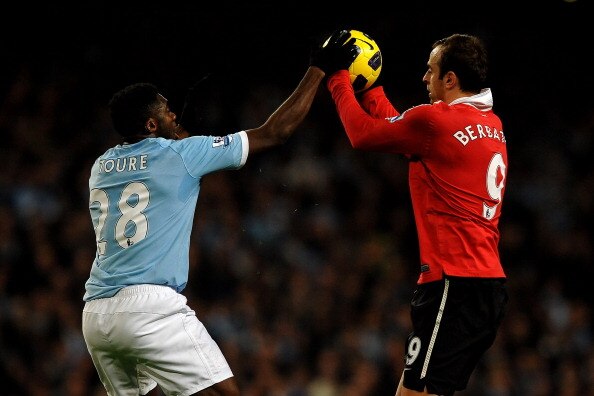 MANCHESTER, UNITED KINGDOM - NOVEMBER 10:   Kolo Toure of Manchester City tries to grab the ball from Dimitar Berbatov of Manchester United during the Barclays Premier League match between Manchester City and Manchester United at the City of Manchester St