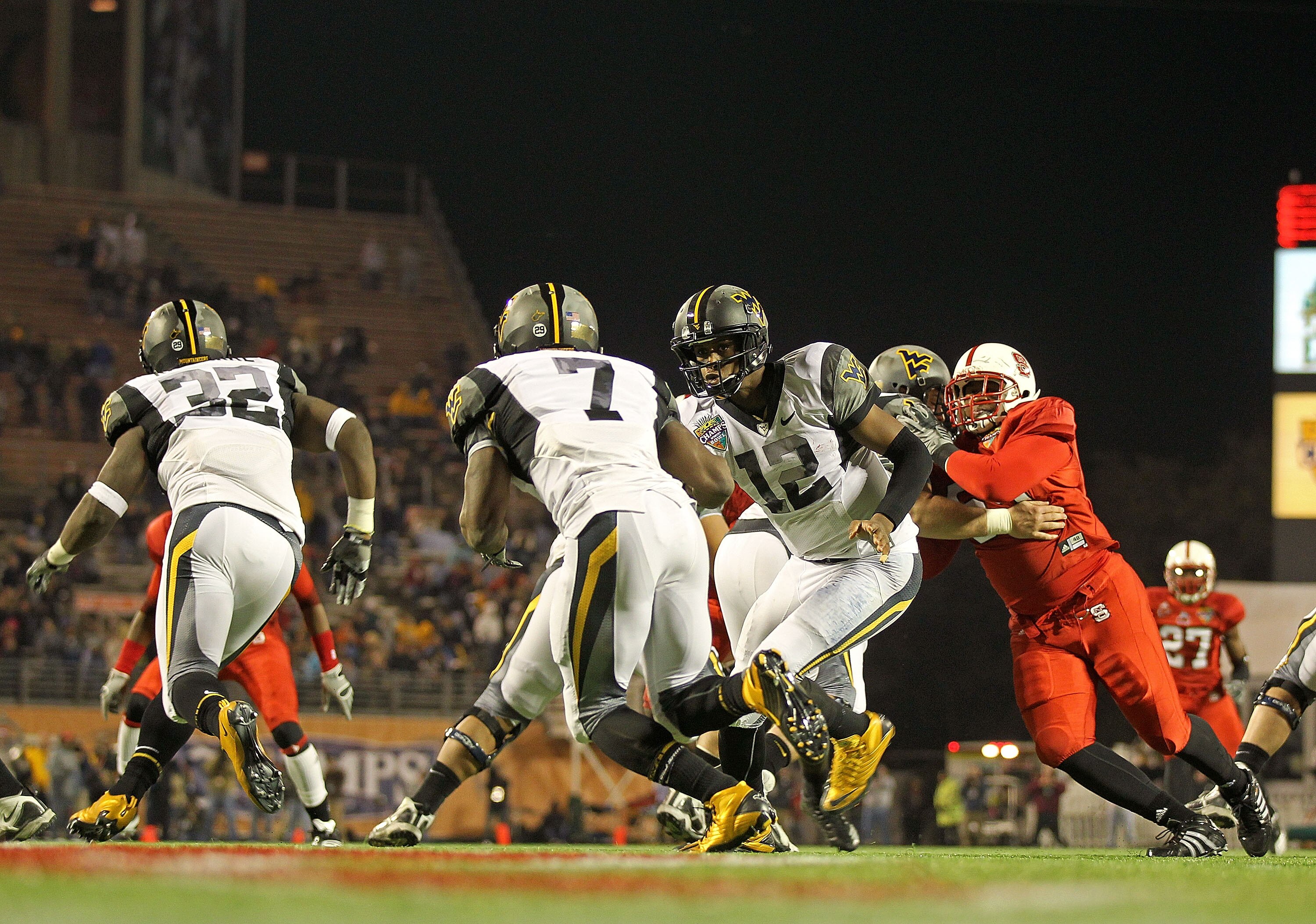 ORLANDO, FL - DECEMBER 28:  Geno Smith #12 of the West Virginia Mountineers hands the ball off to Noel Devine #7 during the Champs Sports Bowl against the North Carolina State Wolfpack at Florida Citrus Bowl Stadium on December 28, 2010 in Orlando, Florid