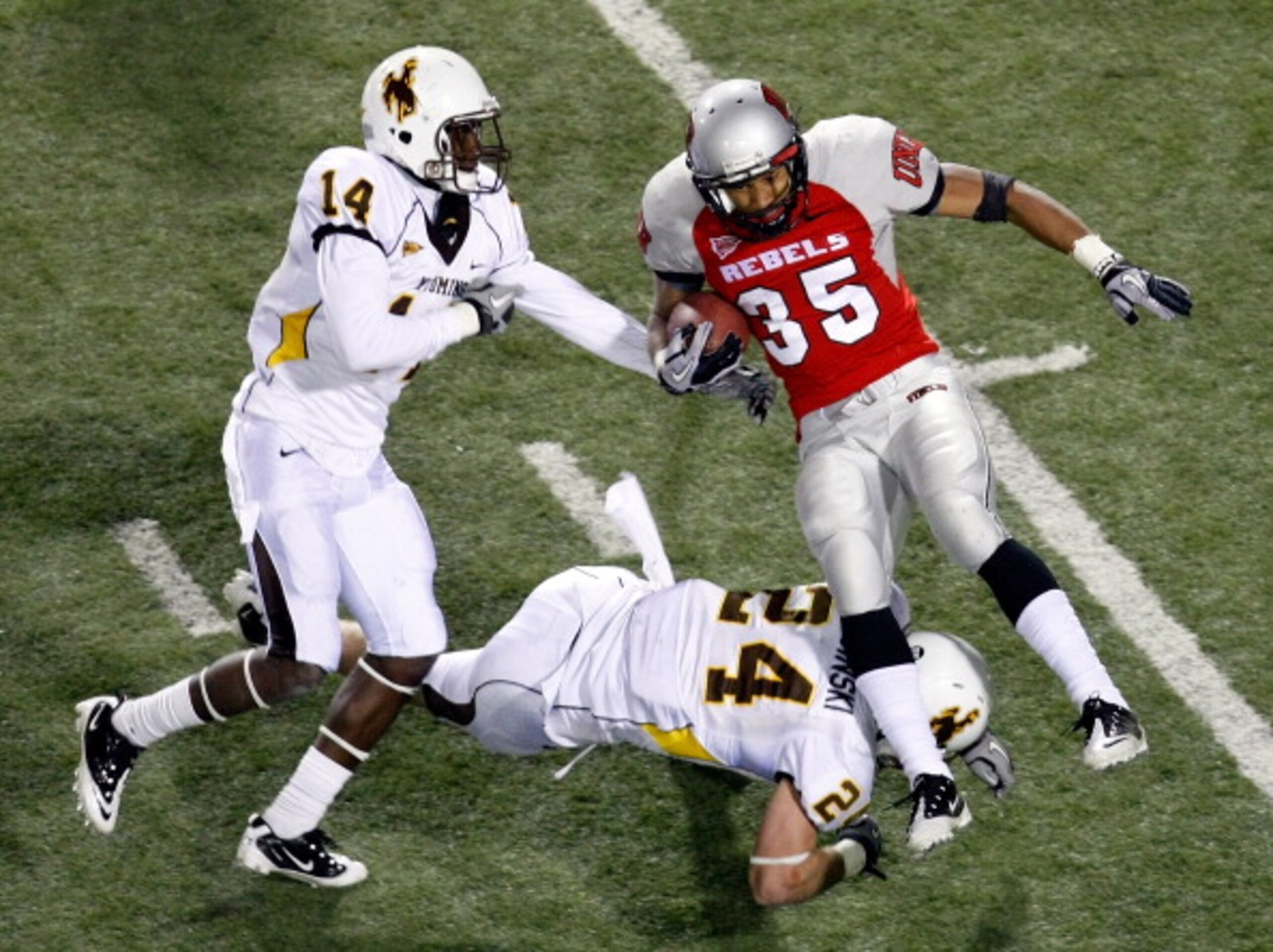 LAS VEGAS - NOVEMBER 13:  Tim Cornett #35 of the UNLV Rebels is tackled by Chris Prosinski #24 and Marqueston Huff #14 of the Wyoming Cowboys during their game at Sam Boyd Stadium November 13, 2010 in Las Vegas, Nevada. Cornett had four touchdowns in UNLV