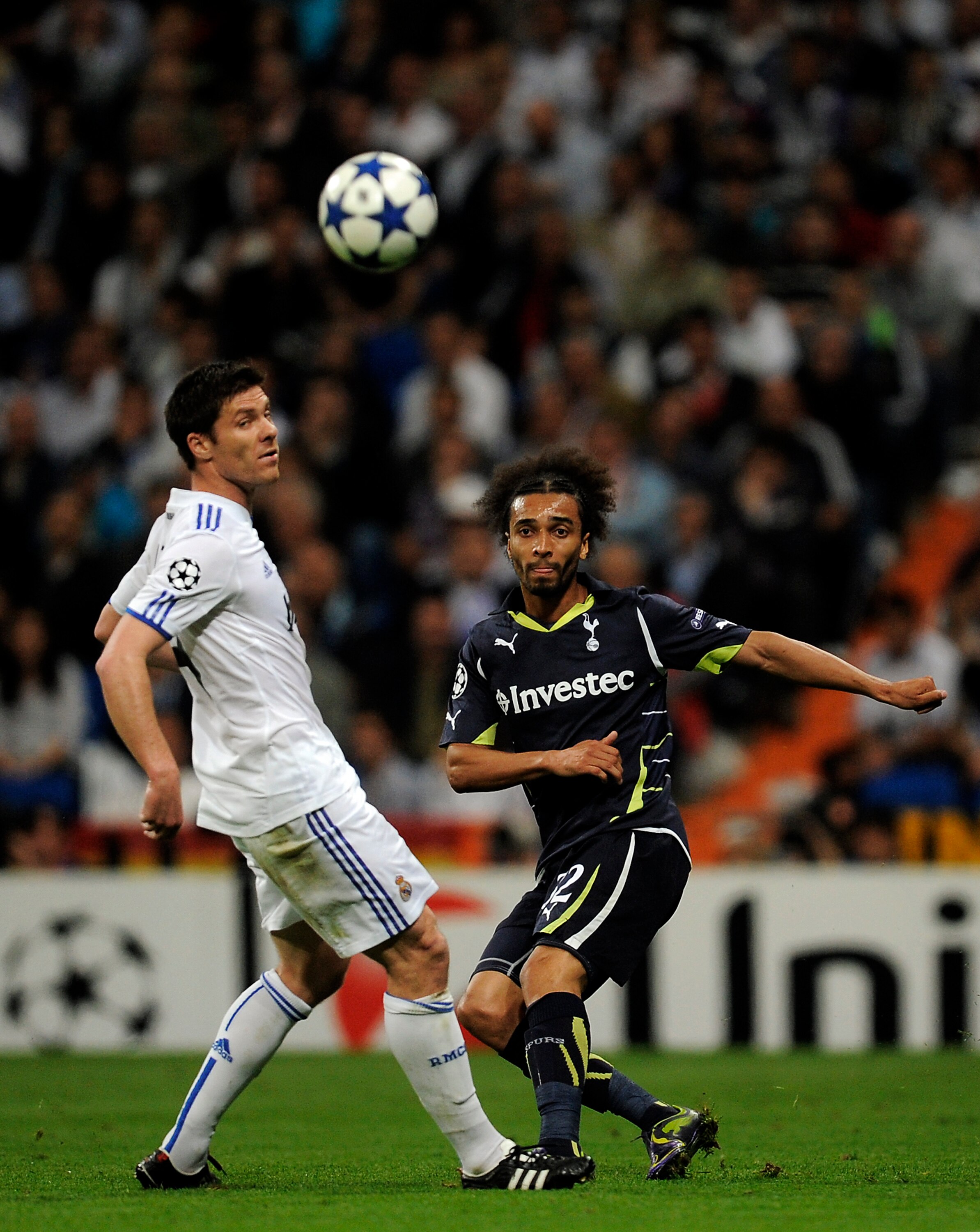 MADRID, SPAIN - APRIL 05:  Benoit Assou-Ekotto of Tottenham Hotspur (R) makes a pass under a challenge by Xabi Alonso of Real Madrid during the UEFA Champions League quarter final first leg match between Real Madrid and Tottenham Hotspur at Estadio Santia