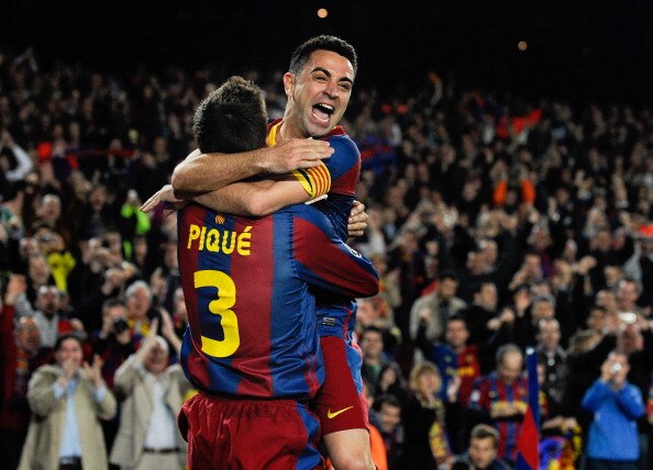 BARCELONA, SPAIN - APRIL 06: Xavi Hernandez of FC Barcelona celebrates with teammate Gerard Pique after Pique scored their team's third goal during the UEFA Champions League quarter final first leg match between Barcelona and Shakhtar Donetsk at the Camp