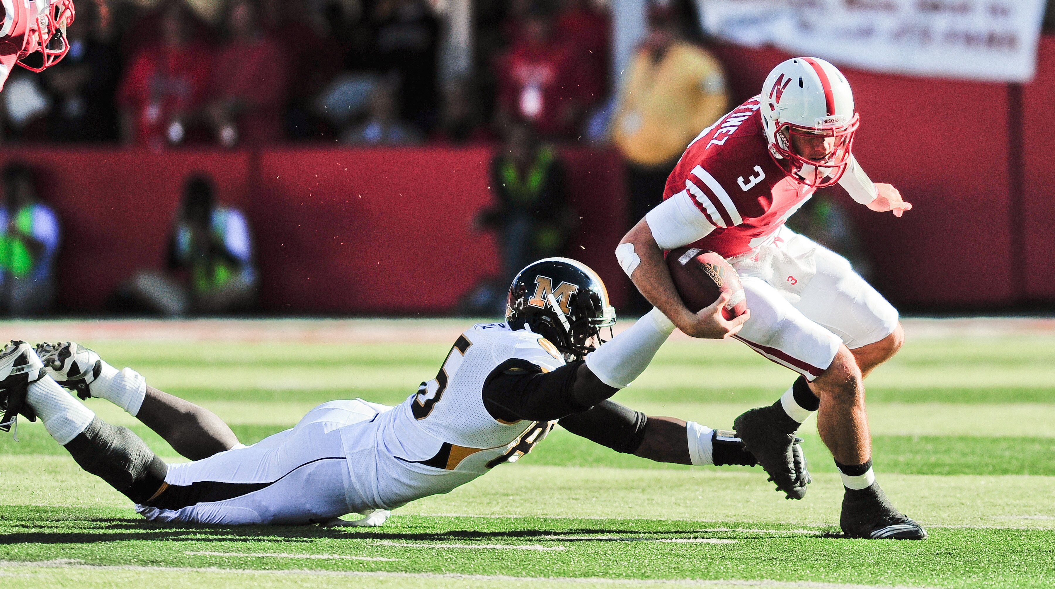LINCOLN, NE - OCTOBER 30: Quarterback Taylor Martinez #3 of the Nebraska Cornhuskers tries to slip the grip of defensive end Aldon Smith #85 of the Missouri Tigers during first half action of their game at Memorial Stadium on October 30, 2010 in Lincoln,