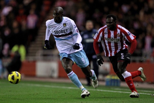 SUNDERLAND, ENGLAND - DECEMBER 05:  Carlton Cole of West Ham United is pursued by John Mensah of Sunderland during the Barclays Premier League match between Sunderland and West Ham United at the Stadium of Light on December 5, 2010 in Sunderland, England.