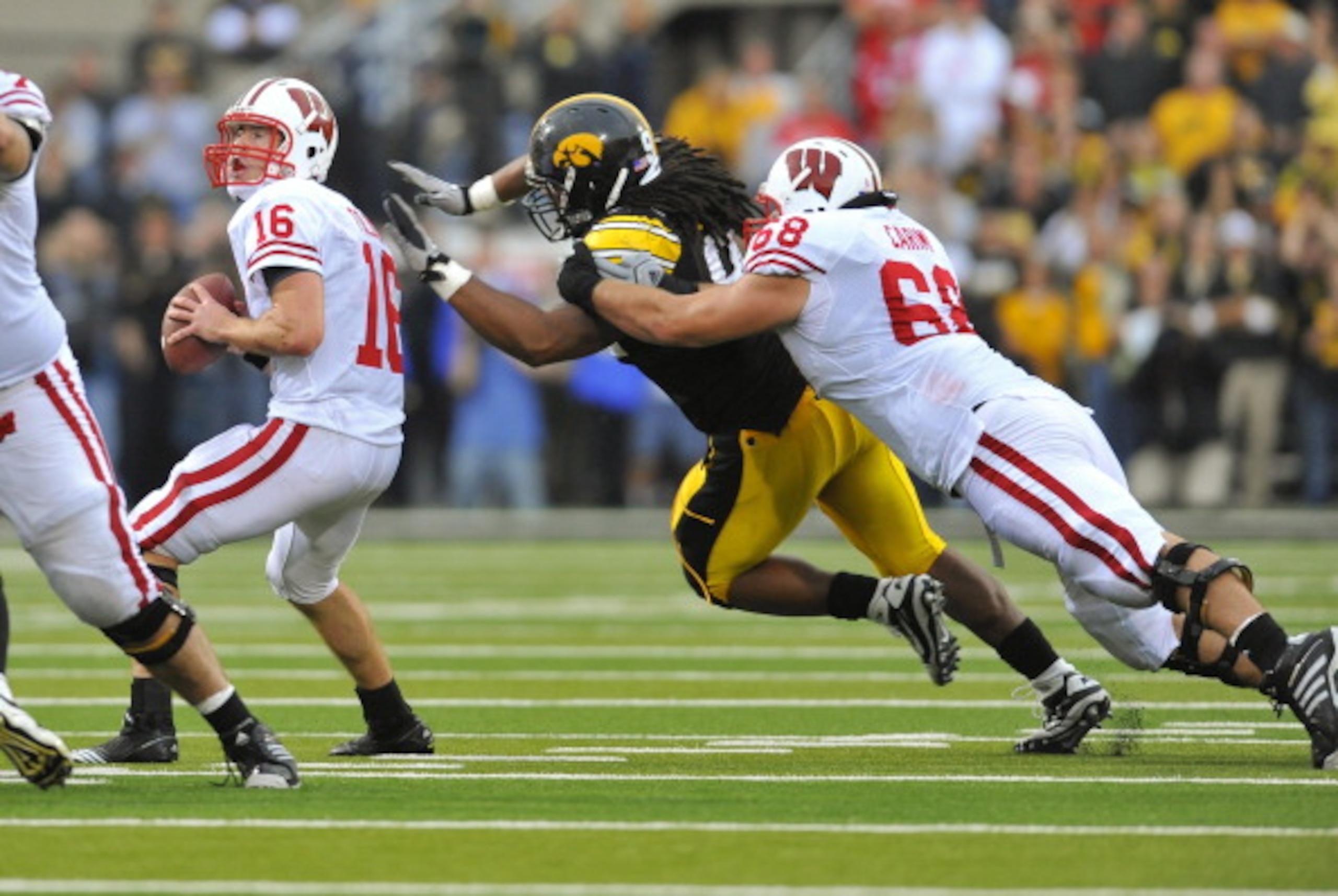 IOWA CITY, IA - OCTOBER 23- Quarterback Scott Tolzien #16 of the Wisconsin Badgers throws under pressure from Defensive lineman Adrian Clayborn #94 of the University of Iowa Hawkeyes as offensive lineman Gabe Carimi #68 defends during the first half of pl