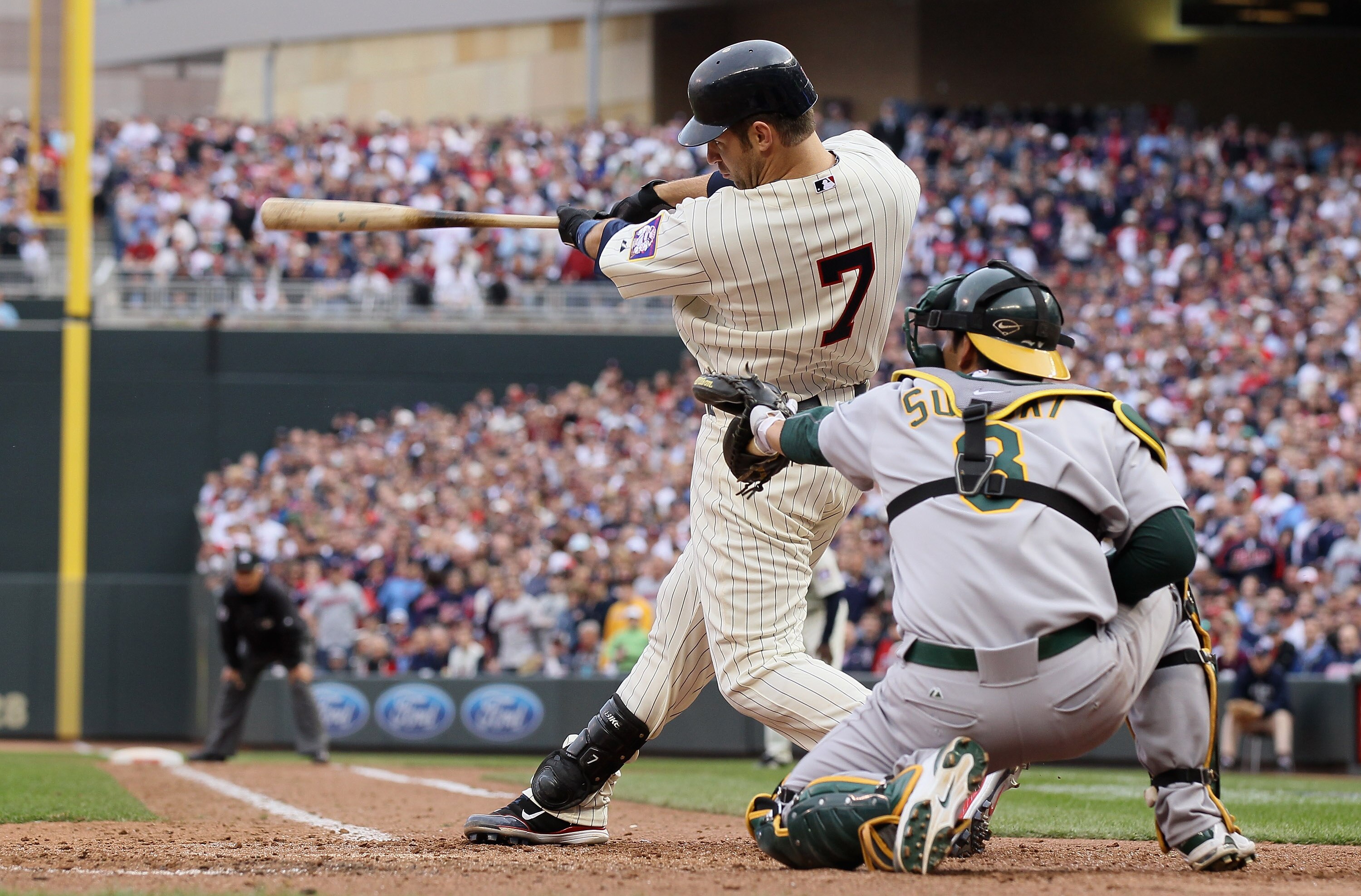 MINNEAPOLIS, MN - APRIL 08:  Joe Mauer #7 of the Minnesota Twins drives in the winning run as Kurt Suzuki #8 of the Oakland Athletics catches during Opening Day on April 8, 2011 at Target Field in Minneapolis, Minnesota. The Minnesota Twins defeated the O