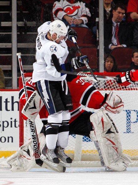 NEWARK, NJ - MARCH 02:  Steven Stamkos #91 of the Tampa Bay Lightning leaps to try to tip in a shot as he crashes into goalie Martin Brodeur #30 of the New Jersey Devils and receives a goaltender interference penalty during the second period of an NHL hoc
