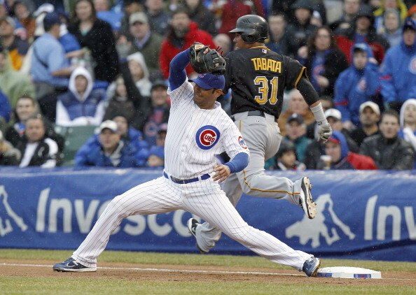 CHICAGO, IL - APRIL 01: Carlos Pena #22 of the Chicago Cubs digs a throw out of the dirt before Jose Tabata #31 of the Pittsburgh Pirates can get to the base during opening day at Wrigley Field on April 1, 2011 in Chicago, Illinois.  (Photo by Gregory Sha