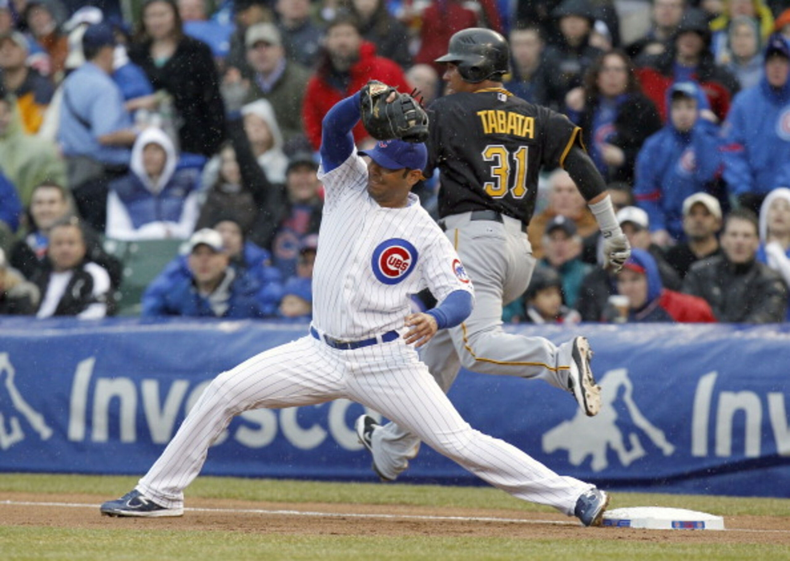 CHICAGO, IL - APRIL 01: Carlos Pena #22 of the Chicago Cubs digs a throw out of the dirt before Jose Tabata #31 of the Pittsburgh Pirates can get to the base during opening day at Wrigley Field on April 1, 2011 in Chicago, Illinois.  (Photo by Gregory Sha