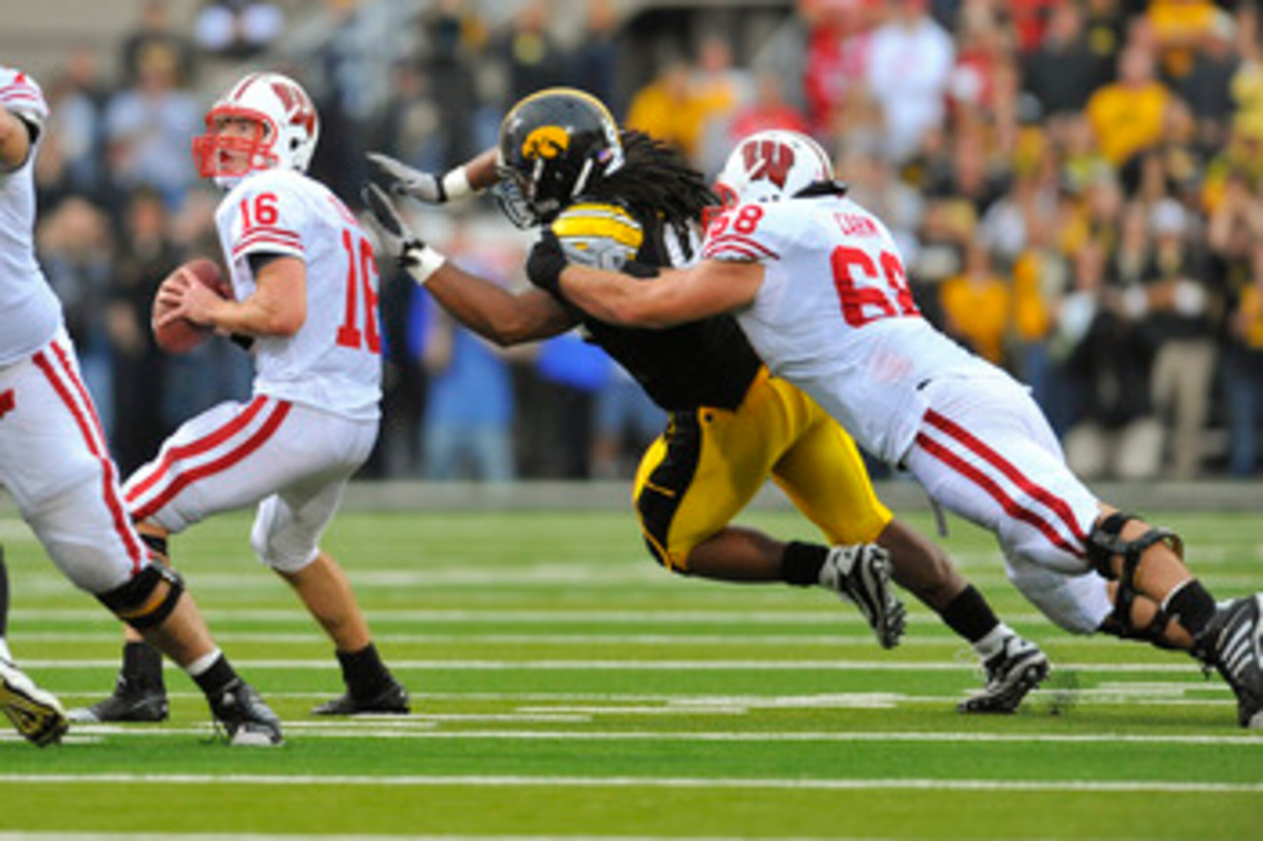 IOWA CITY, IA - OCTOBER 23- Quarterback Scott Tolzien #16 of the Wisconsin Badgers throws under pressure from Defensive lineman Adrian Clayborn #94 of the University of Iowa Hawkeyes as offensive lineman Gabe Carimi #68 defends during the first half of pl