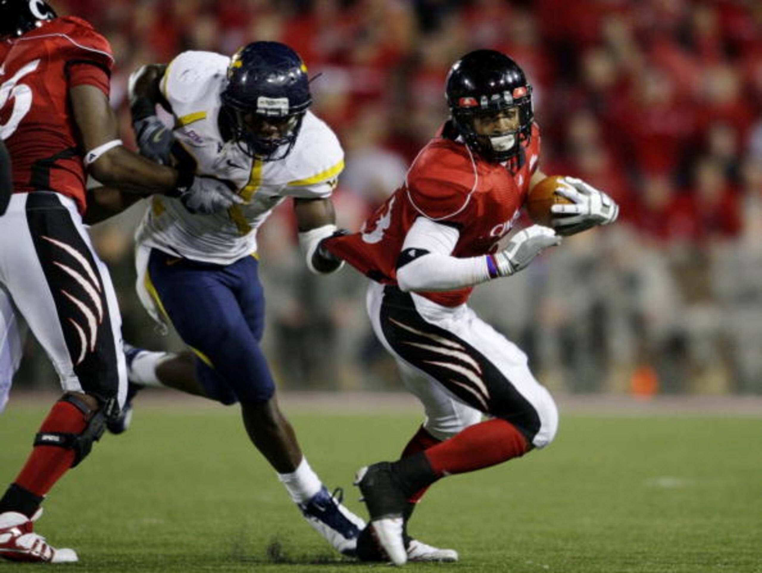 CINCINNATI - NOVEMBER 13: Isaiah Pead #23 of the Cincinnati Bearcats is grabbed by J.T. Thomas #30 of the West Virginia Mountaineers in the fourth quarter of the game at Nippert Stadium on November 13, 2009 in Cincinnati, Ohio. (Photo by Andy Lyons/Getty