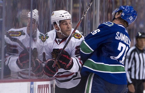 VANCOUVER, CANADA - FEBRUARY 4: Mikael Samuelsson #26 of the Vancouver Canucks hits Jake Dowell #28 of the Chicago Blackhawks into the side boards during the second period in NHL action on February 04, 2011 at Rogers Arena in Vancouver, British Columbia, 