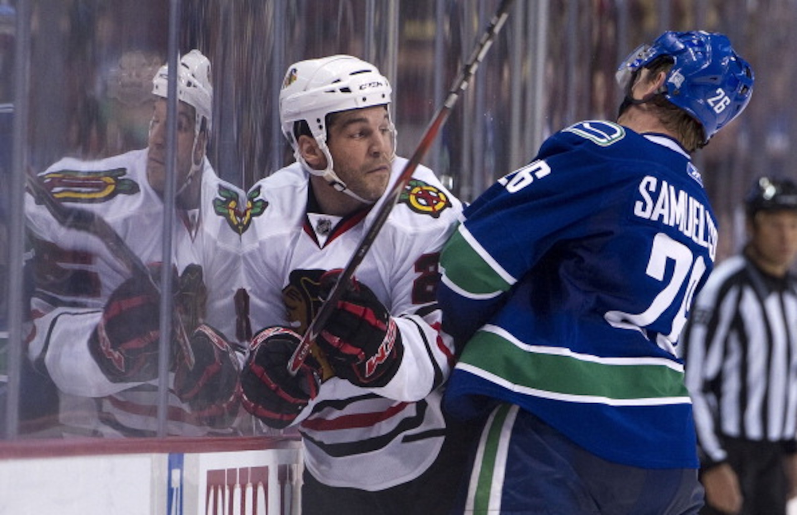 VANCOUVER, CANADA - FEBRUARY 4: Mikael Samuelsson #26 of the Vancouver Canucks hits Jake Dowell #28 of the Chicago Blackhawks into the side boards during the second period in NHL action on February 04, 2011 at Rogers Arena in Vancouver, British Columbia, 