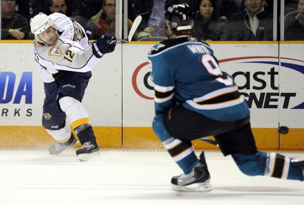 SAN JOSE, CA - MARCH 8: Mike Fisher #12 of the Nashville Predators gets his shot off pass Ian White #9 of the San Jose Sharks in overtime of an NHL hockey game at the HP Pavilion on March 8, 2011 in San Jose, California. The Sharks won the game in overtim