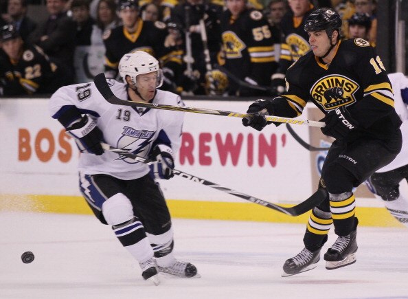 BOSTON, MA - MARCH 03:  Nathan Horton #18 of the Boston Bruins clears the puck as Dominic Moore #19 of the Tampa Bay Lightning nearly is hit on March 3, 2011 at the TD Garden in Boston, Massachusetts.  (Photo by Elsa/Getty Images)