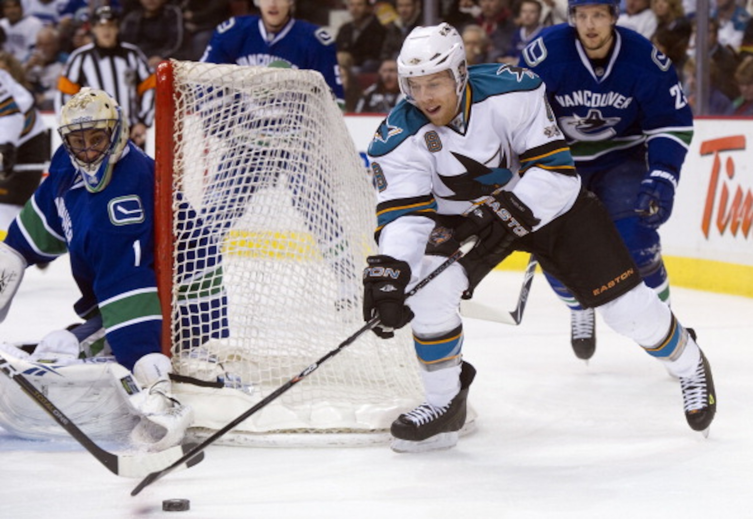 VANCOUVER, CANADA - JANUARY 20: Joe Pavelski #8 of the San Jose Sharks tries to get a handle of the puck while attempting a wrap around on goalie Roberto Luongo #1 of the Vancouver Canucks during the first period in NHL action on January 20, 2011 at Roger